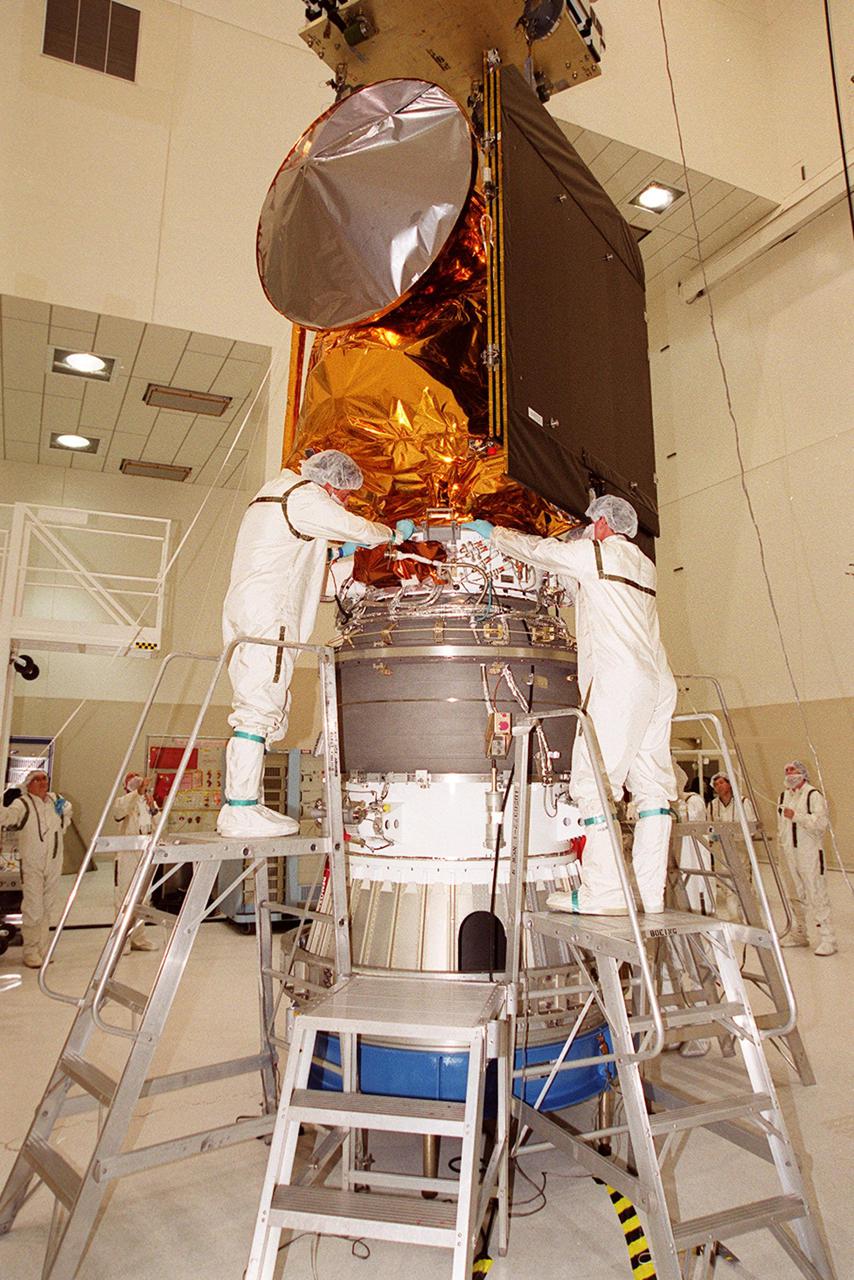 Workers in the Space Assembly and Encapsulation Facility 2 check the connections of the Mars Odyssey Orbiter on the third stage of a Delta rocket. Visible above is the cone-shaped high gain antenna and the black solar array assembly. The Mars Odyssey is scheduled for launch at 11:02 a.m. EDT April 7, 2001, aboard a Delta II rocket from Launch Pad 17-A, Cape Canaveral Air Force Station. The spacecraft is designed to map the surface of Mars