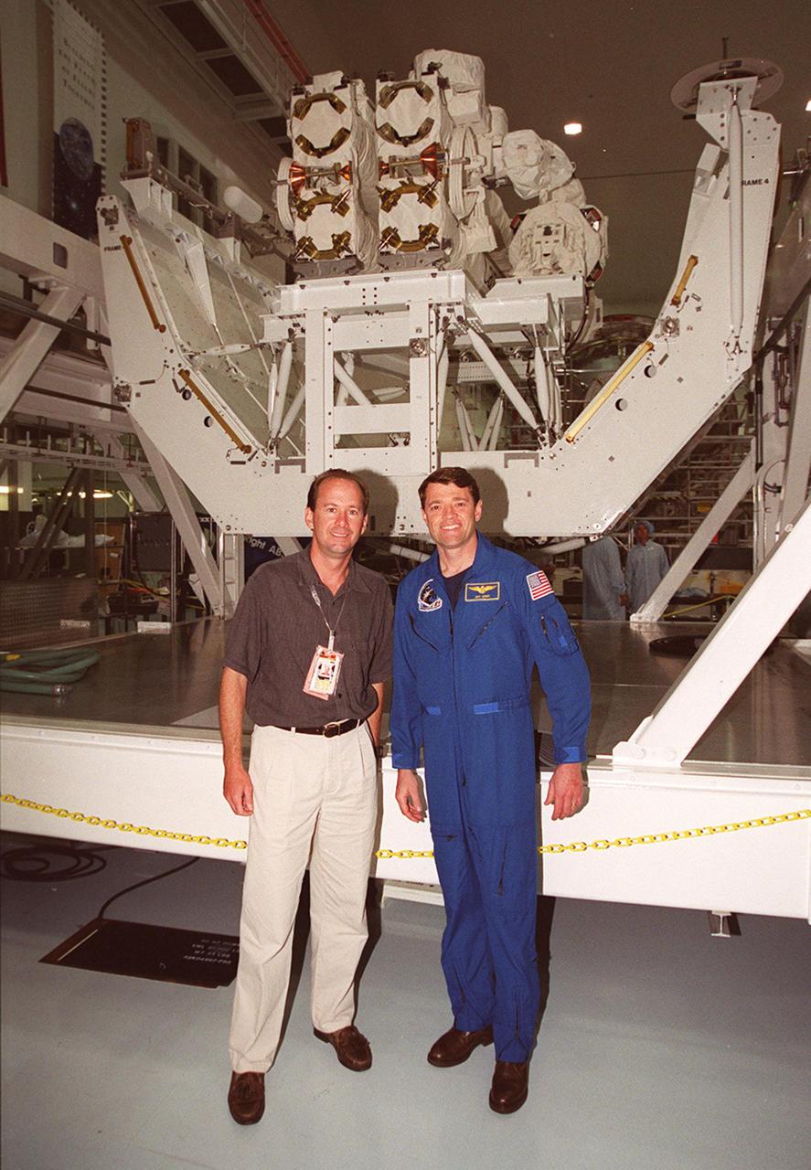 KSC’s PAO videographer, Glenn Benson (left) and STS-100 Pilot Jeffrey S. Ashby pose in front of the Canadian robotic arm, SSRMS, in the Space Station Processing Facility. The STS-100 crew is at KSC for Terminal Countdown Demonstration Test activities that include emergency escape training at the pad and a simulated launch countdown. The mission is carrying the Multi-Purpose Logistics Module Raffaello and the SSRMS, to the International Space Station. Raffaello carries six system racks and two storage racks for the U.S. Lab. The SSRMS is crucial to the continued assembly of the orbiting complex. Launch of mission STS-100 is scheduled for April 19 at 2:41 p.m. EDT from Launch Pad 39A