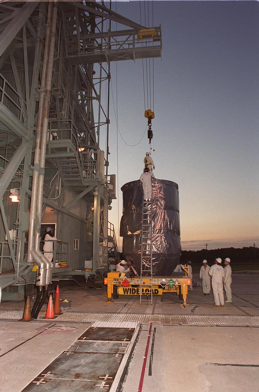 At sunrise on Launch Pad 17-A, Cape Canaveral Air Force Station, workers begin attaching a crane to the top of the Mars Odyssey orbiter. The spacecraft will be lifted up the gantry and mated with the Delta II rocket. The spacecraft will map the Martian surface in search of geological features that could indicate the presence of water, now or in the past, and may contribute significantly toward understanding what will be necessary for a more sophisticated exploration of Mars. Launch is scheduled for 11:02 a.m. EDT April 7