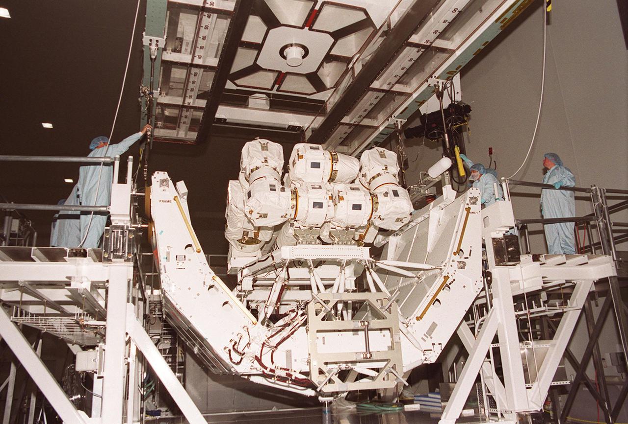 In the Space Station Processing Facility, an overhead crane moves into place over the Canadian robotic arm, SSRMS, and its pallet. The crane will lift the SSRMS and move it to the payload canister. The arm is 57.7 feet (17.6 meters) long when fully extended and has seven motorized joints. It is capable of handling large payloads and assisting with docking the Space Shuttle. The SSRMS is self-relocatable with a Latching End Effector, so it can be attached to complementary ports spread throughout the Station’s exterior surfaces. The SSRMS is part of the payload on mission STS-100, scheduled to launch April 19 at 2:41 p.m. EDT from Launch Pad 39A, KSC