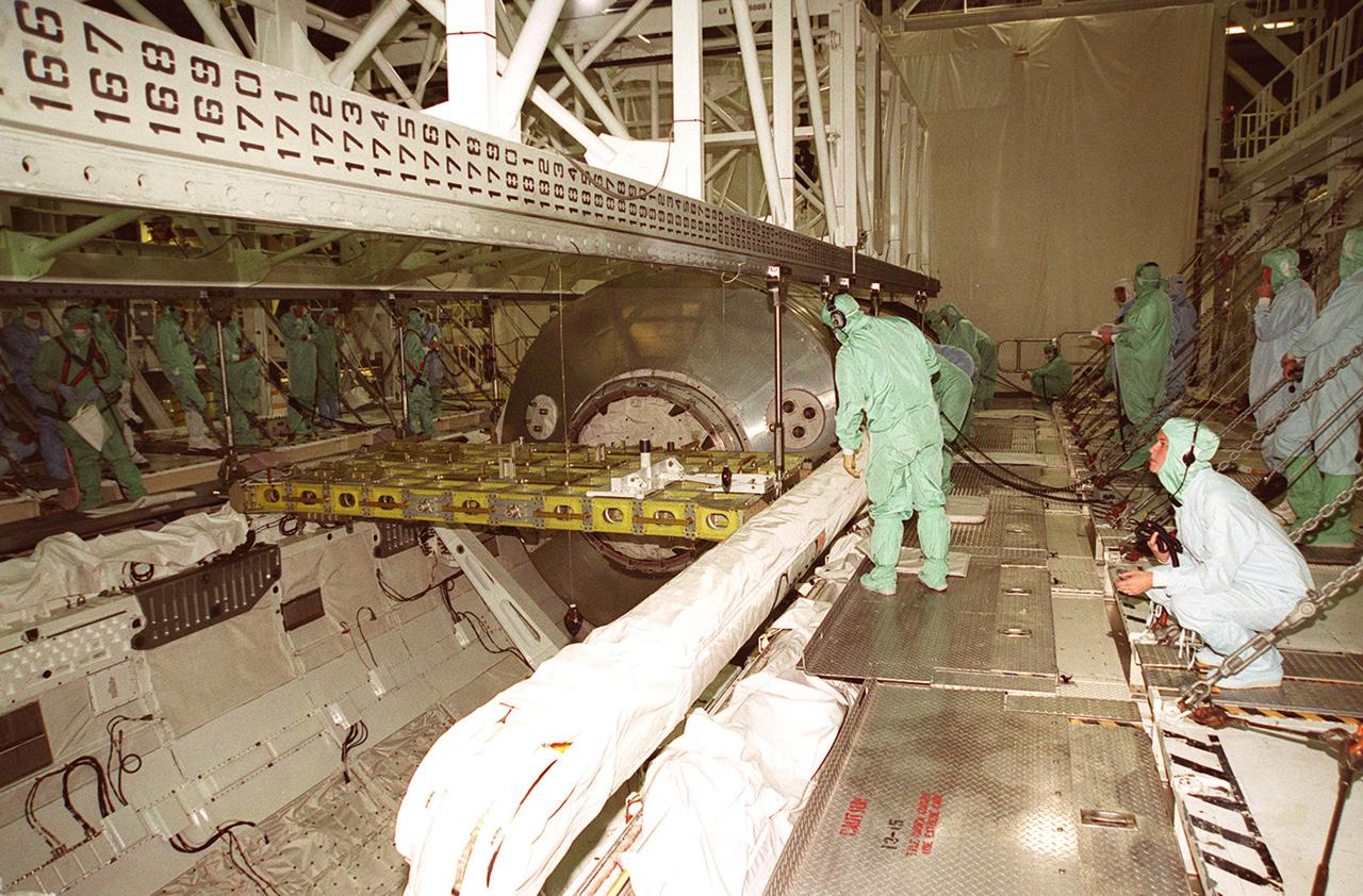 KENNEDY SPACE CENTER, FLA. -- Workers in the Orbiter Processing Facility bay 2 check the attachments on the overhead crane to the Multi-Purpose Logistics Module Leonardo and the integrated cargo carrier behind it sitting in Discovery’s payload bay. The MPLM has just returned from its first round trip to the International Space Station on mission STS-102. Attached to the length of the payload bay, in front of Leonardo, is the robotic arm that was used to remove and position Leonardo on the ISS. Leonardo will be lifted from the payload bay and transferred to the SSPF to prepare it for future missions. The MPLM serves as a cargo van, carrying equipment and supplies to the Space Station