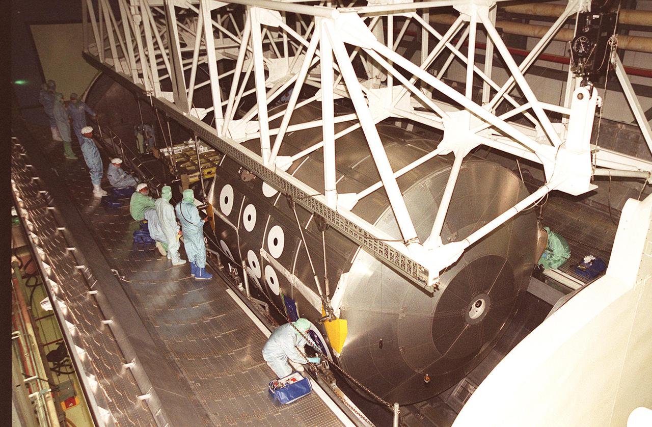 KENNEDY SPACE CENTER, FLA. -- Workers in the Orbiter Processing Facility bay 2 keep watch as an overhead crane lowers the Multi-Purpose Logistics Module Leonardo and the integrated cargo carrier behind it into a payload canister. The MPLM has just returned from its first round trip to the International Space Station on mission STS-102. The MPLM will be transferred to the SSPF to prepare it for future missions