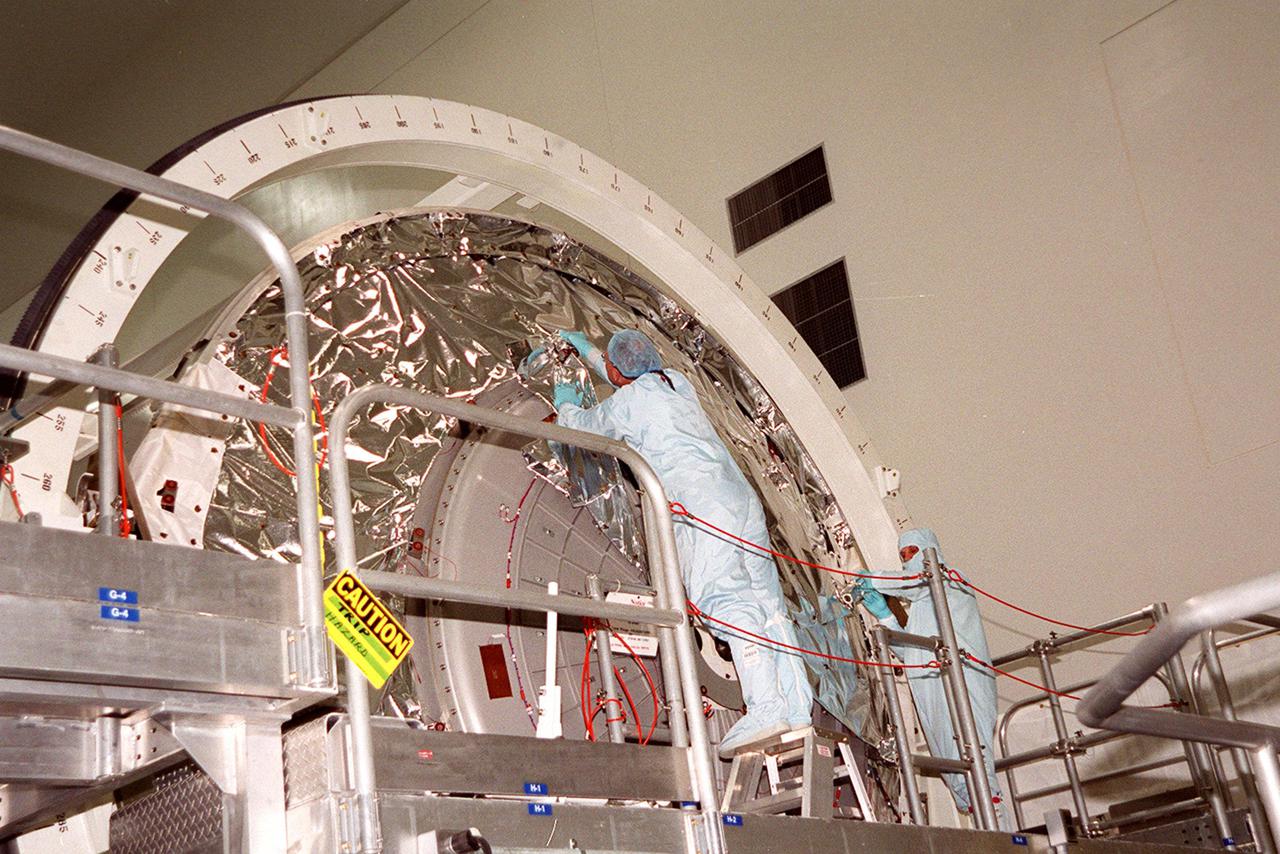 KENNEDY SPACE CENTER, FLA. -- Workers in the Space Station Processing Facility begin unwrapping the protective cover over the end of Multi-Purpose Logistics Module Leonardo so they can open the hatch and access the inside. The MPLM has just returned from its maiden voyage to the International Space Station aboard Discovery on mission STS-102. Leonardo is one of three MPLMs built by the Italian Space Agency to serve as “cargo vans” to the Station, carrying supplies and equipment. In the SSPF, Leonardo will be prepared for a future mission