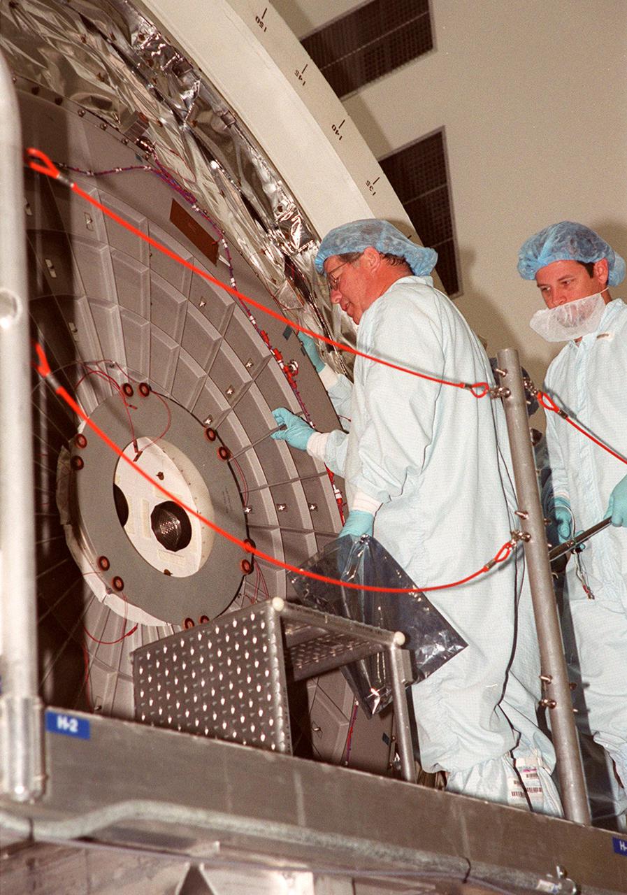 KENNEDY SPACE CENTER, FLA. -- Workers in the Space Station Processing Facility look at the hatch on Multi-Purpose Logistics Module Leonardo. The MPLM has just returned from its maiden voyage to the International Space Station aboard Discovery on mission STS-102. Leonardo is one of three MPLMs built by the Italian Space Agency to serve as “cargo vans” to the Station, carrying supplies and equipment. In the SSPF, Leonardo will be prepared for a future mission