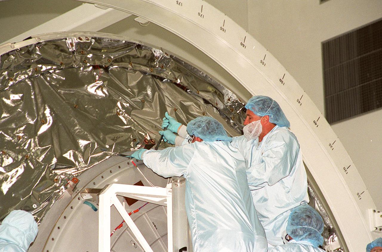 KENNEDY SPACE CENTER, FLA. -- Workers in the Space Station Processing Facility loosen the hatch on Multi-Purpose Logistics Module Leonardo. The MPLM has just returned from its maiden voyage to the International Space Station aboard Discovery on mission STS-102. Leonardo is one of three MPLMs built by the Italian Space Agency to serve as “cargo vans” to the Station, carrying supplies and equipment. In the SSPF, Leonardo will be prepared for a future mission