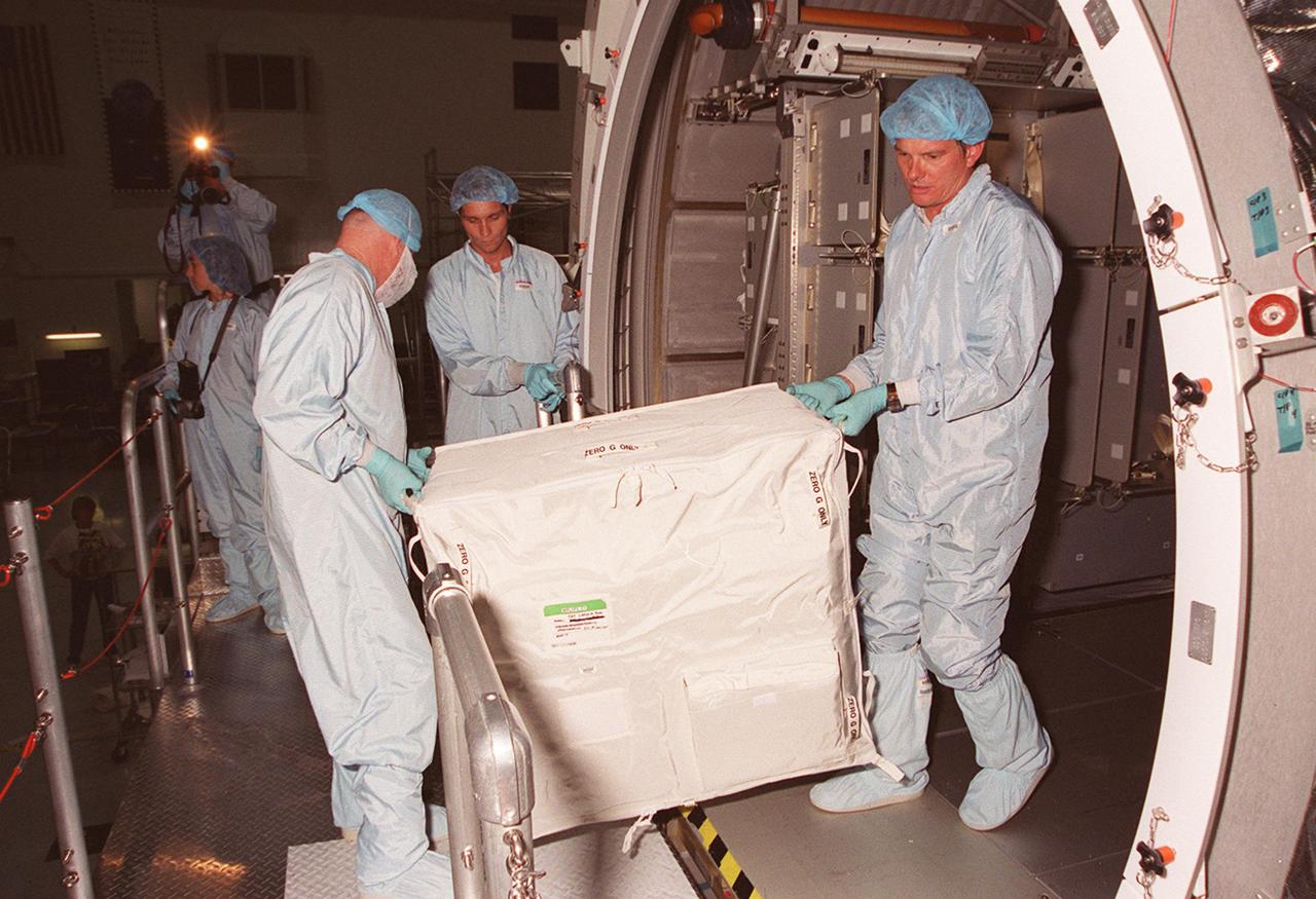 KENNEDY SPACE CENTER, FLA. -- Inside the Multi-Purpose Logistics Module Leonardo, which is in the Space Station Processing Facility, workers remove one of the containers returned from the International Space Station on mission STS-102. The MPLM brought back to KSC nearly a ton of trash and excess equipment from the Space Station. Leonardo is one of three MPLMs built by the Italian Space Agency to serve as “cargo vans” to the Station, carrying supplies and equipment. In the SSPF, Leonardo will be prepared for a future mission
