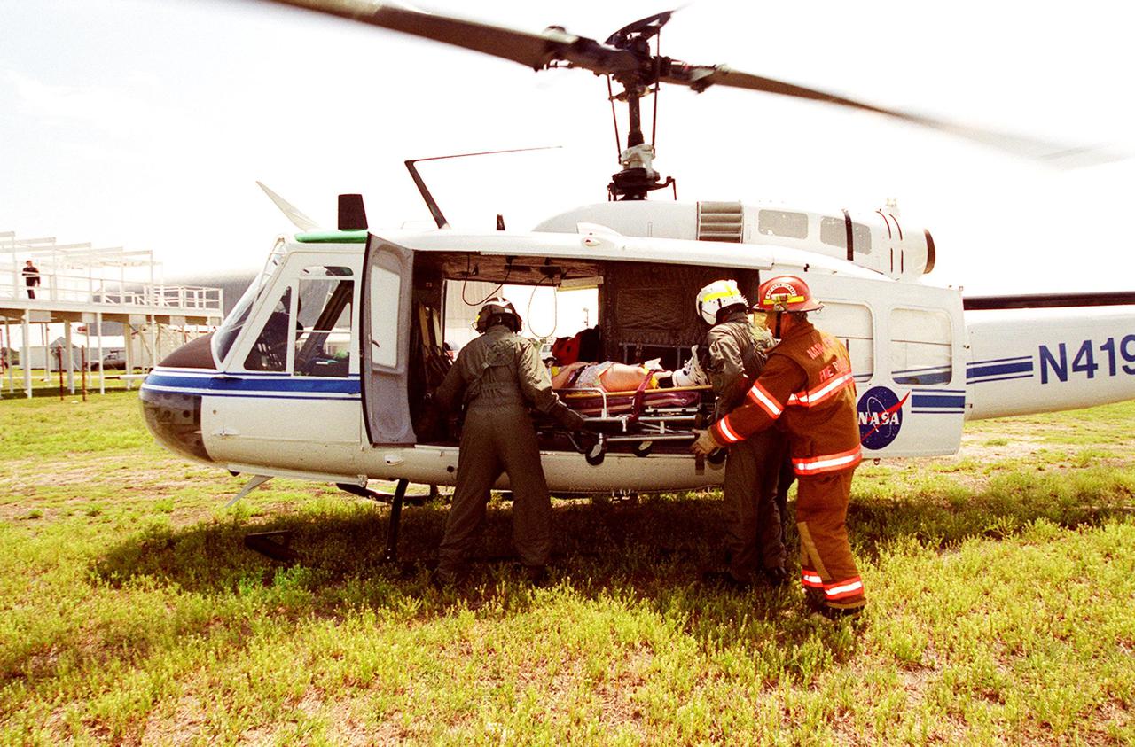 KENNEDY SPACE CENTER, FLA. -- Rescue personnel place a “victim” in a medevac helicopter during a staged mass casualty exercise in the Launch Complex 39 area. Employees are playing roles in the fictitious sniper attack that is being staged to validate capabilities of KSC’s fire, medical, helicopter transport and security personnel to respond to such an event