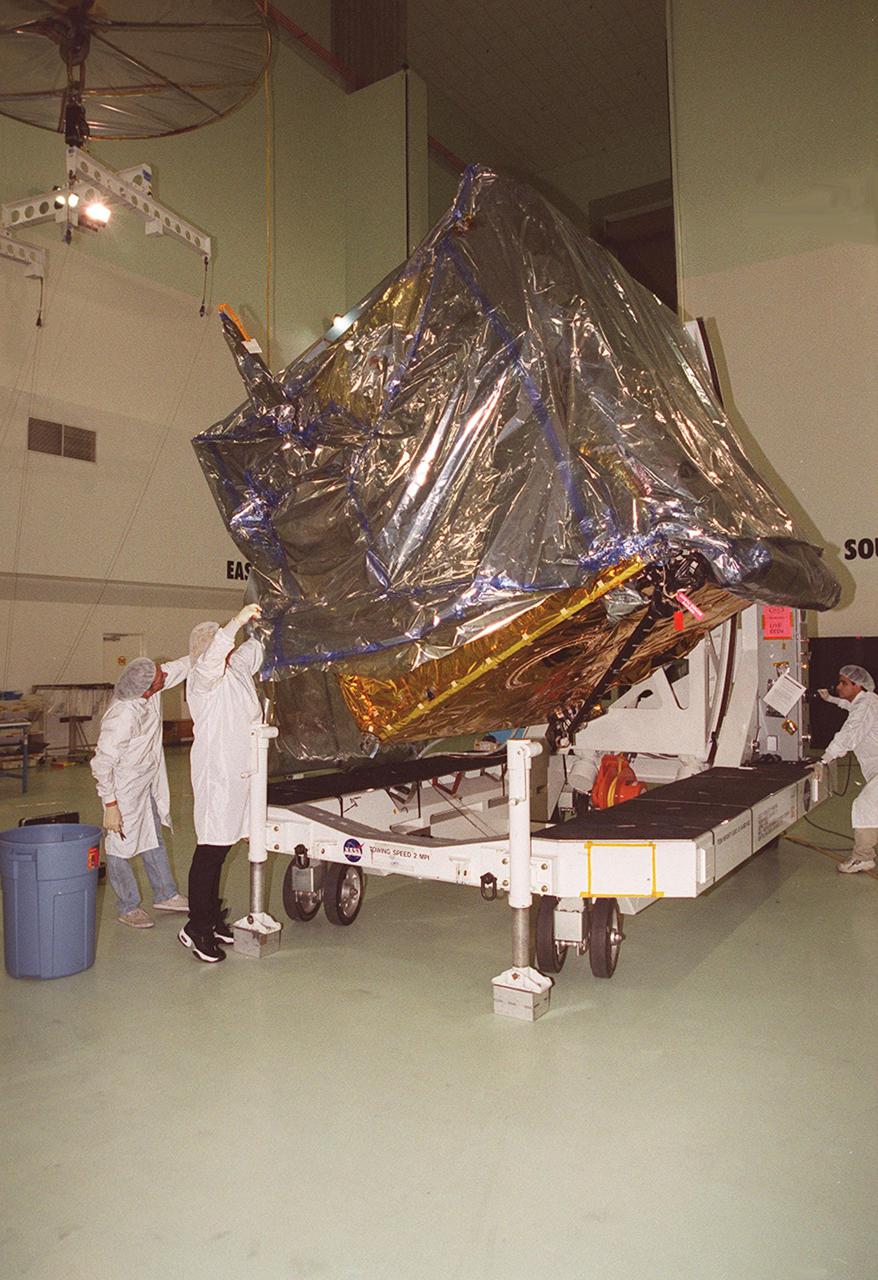 At Astrotech, Titusville, Fla., the GOES-M (Geostationary Operational Environmental Satellite) satellite is tilted on a workstand so that workers can remove part of the protective cover. The GOES-M provides weather imagery and quantitative sounding data used to support weather forecasting, severe storm tracking and meteorological research. The satellite will undergo testing at Astrotech before its scheduled launch July 12 on an Atlas-IIA booster, Centaur upper stage from Cape Canaveral Air Force Station