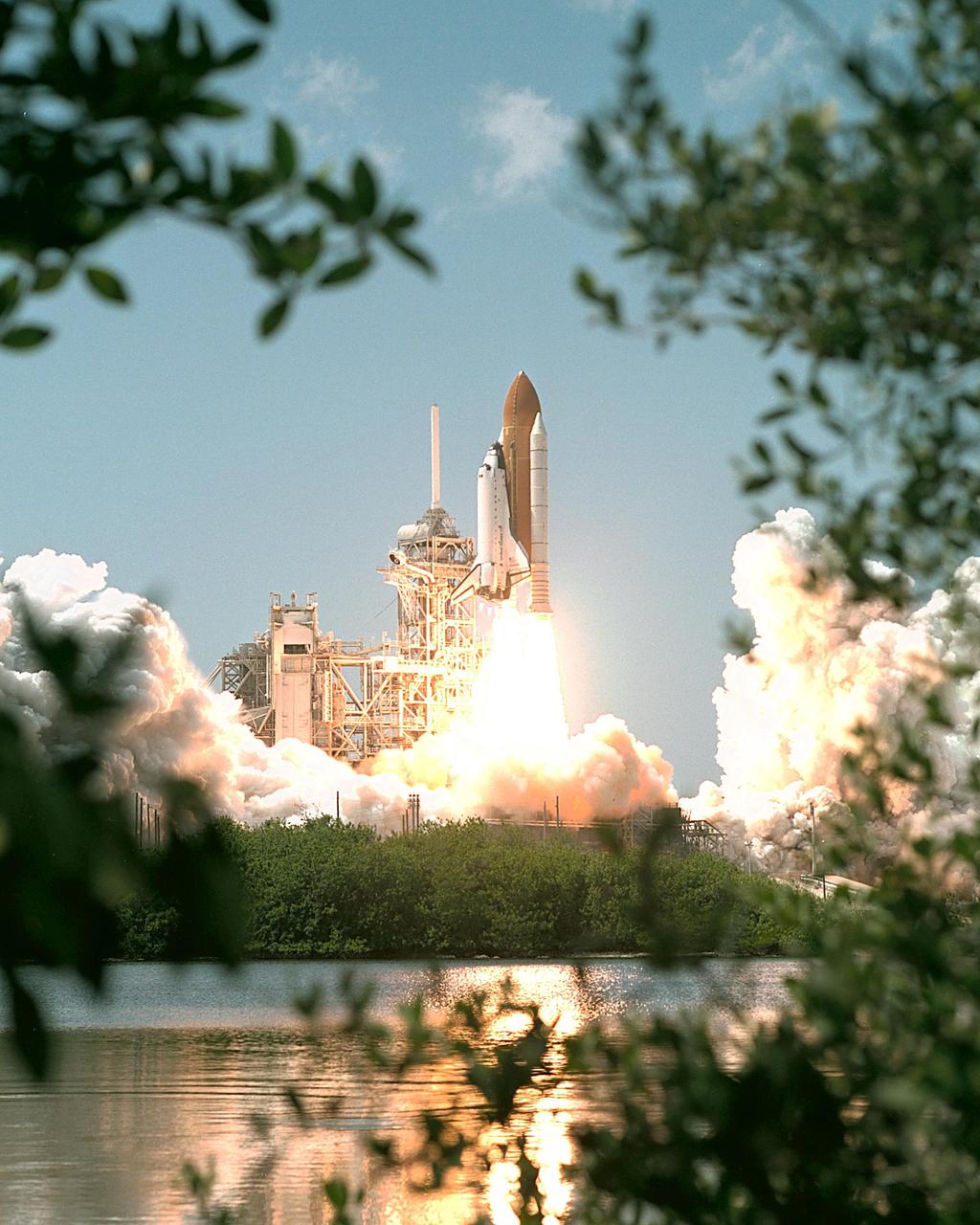 KENNEDY SPACE CENTER, FLA. -- Spring leaves frame Space Shuttle Endeavour as the water captures the launch of mission STS-100. Liftoff of Endeavour on the ninth flight to the International Space Station occurred at 2:40:42 p.m. EDT. The 11-day mission will deliver and integrate the Spacelab Logistics Pallet_Launch Deployment Assembly, which includes the Space Station Remote Manipulator System and the UHF Antenna. The mission includes two planned spacewalks for installation of the SSRMS on the Station. Also onboard is the Multi-Purpose Logistics Module Raffaello, carrying resupply stowage racks and resupply_return stowage platforms