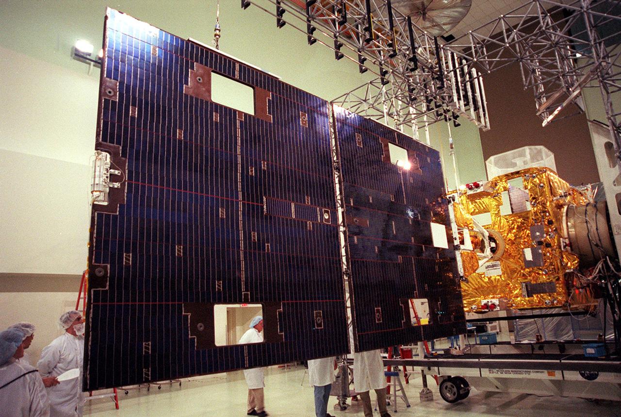 Workers at Astrotech, Titusville, Fla., take a close look at the solar panel on the GOES-M satellite. The GOES-M provides weather imagery and quantitative sounding data used to support weather forecasting, severe storm tracking and meteorological research. The satellite is scheduled to launch July 12 on an Atlas-IIA booster, Centaur upper stage from Cape Canaveral Air Force Station