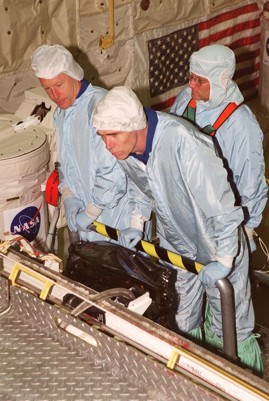 KENNEDY SPACE CENTER, FLA. -- During Crew Equipment Interface Test activities in Orbiter Processing Facility bay 2, members of the STS-105 crew take a close look at equipment and some of the payload. From left are Mission Specialists Patrick Forrester and Daniel Barry. Behind them is a Boeing technician. STS-105 is the 11th mission to the International Space Station. The payload includes the Multi-Purpose Logistics Module Leonardo, which was built by the Italian Space Agency. Leonardo will be outfitted with 12 racks of experiments and equipment. Discovery is scheduled to launch July 12 from Launch Pad 39A