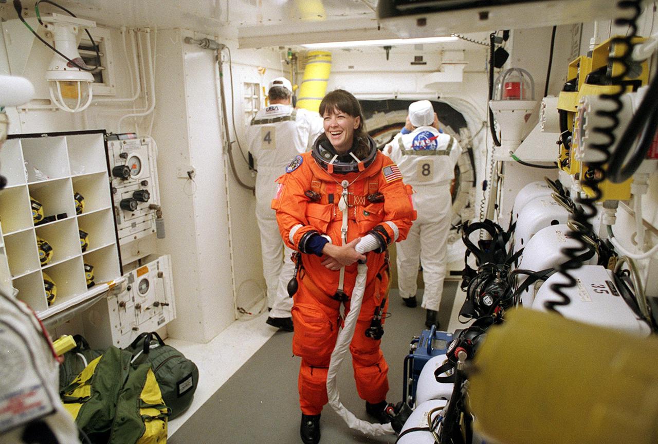 KENNEDY SPACE CENTER, Fla. -- In the White Room, STS-104 Mission Specialist Janet Lynn Kavandi (center) shares a laugh with closeout crew members before entering Space Shuttle Atlantis. The White Room is an environmental chamber at the end of the Orbiter Access Arm that provides entry into the orbiter on the launch pad. Atlantis lifted off from Launch Pad 39B on time at 5:03:59 a.m. EDT. The 10th assembly flight to the International Space Station, the primary payload on the mission is the joint airlock module, which will require two spacewalks to attach it to the Space Station. The airlock will be the primary path for Space Station spacewalk entry and departure for U.S. spacesuits, and will also support the Russian Orlan spacesuit for EVA activity