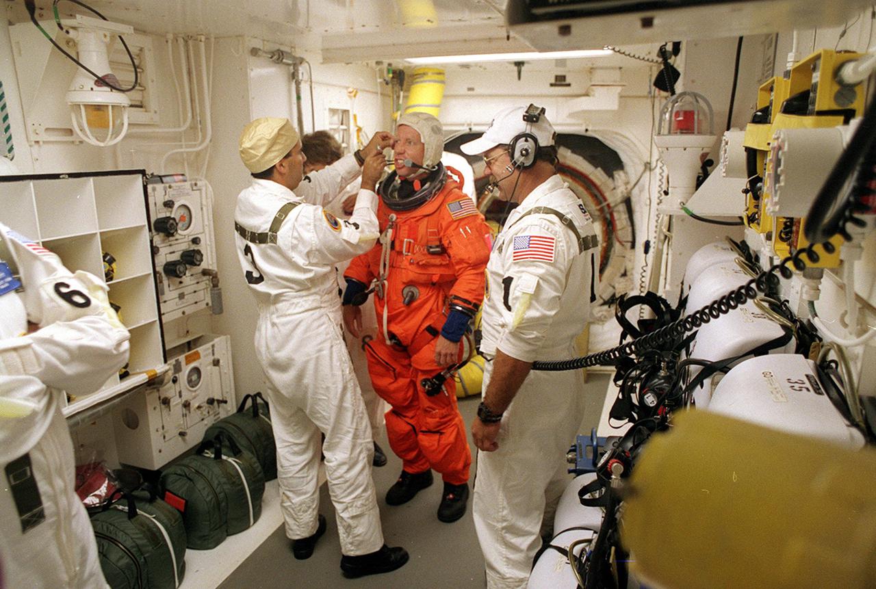 KENNEDY SPACE CENTER, Fla. -- In the White Room, STS-104 Commander Steven W. Lindsey (center) is helped by closeout crew members before entering Space Shuttle Atlantis. The White Room is an environmental chamber at the end of the Orbiter Access Arm that provides entry into the orbiter on the launch pad. Atlantis lifted off from Launch Pad 39B on time at 5:03:59 a.m. EDT. The 10th assembly flight to the International Space Station, the primary payload on the mission is the joint airlock module, which will require two spacewalks to attach it to the Space Station. The airlock will be the primary path for Space Station spacewalk entry and departure for U.S. spacesuits, and will also support the Russian Orlan spacesuit for EVA activity