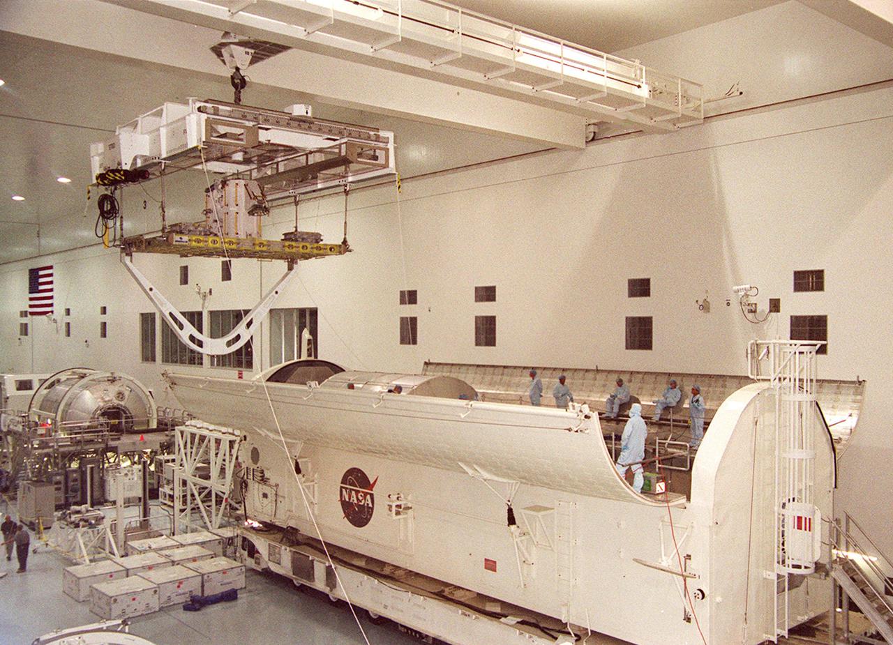 KENNEDY SPACE CENTER, Fla. -- An overhead crane in the Space Station Processing Facility moves the Integrated Cargo Carrier toward the payload canister (right). The ICC holds several payloads for mission STS-105, the Early Ammonia Servicer and two experiment containers. The ICC will join the Multi-Purpose Logistics Module Leonardo already in the payload canister for transport to Launch Pad 39A where they will be placed in the payload bay of Space Shuttle Discovery. Launch of STS-105 is scheduled for 5:38 p.m. EDT Aug. 9