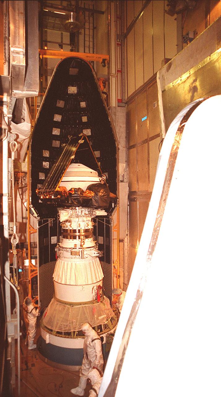 KENNEDY SPACE CENTER, Fla. -- Inside the mobile service tower at Launch Complex 17-A, Cape Canaveral Air Force Station, the Genesis spacecraft is being encapsulated inside the fairing. Workers check the fittings on the first half. The second half is in the foreground. Genesis is 7.5 feet (2.3 meters) long and 6.6 feet (2 meters) wide, with a wingspan of solar array 26 feet (7.9 meters) tip to tip. Genesis will be on a robotic NASA space mission to collect and return to Earth just 10 to 20 micrograms -- or the weight of a few grains of salt -- of solar wind, invisible charged particles that flow outward from the Sun. This treasured smidgen of the Sun will be preserved in a special laboratory for study by scientists over the next century in search of answers to fundamental questions about the exact composition of our star and the birth of our solar system. The sample return capsule is 4.9 feet (1.5 meters) in diameter and 52 inches (1.31 meters) tall. The Genesis launch is scheduled for 12:36 p.m. EDT on July 30 from CCAFS