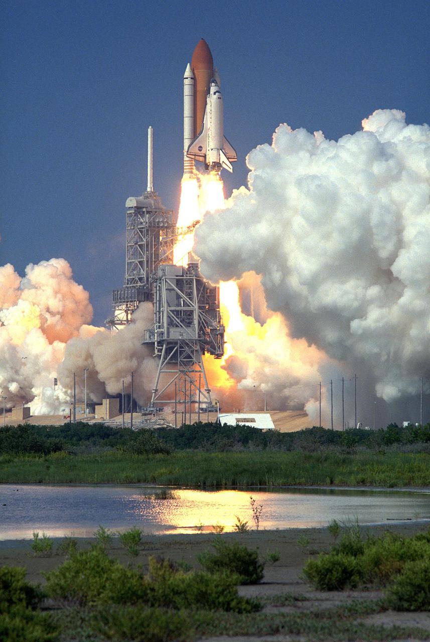 KENNEDY SPACE CENTER, Fla. -- Smoke billows out from Launch Pad 39A as Space Shuttle Discovery soars into the blue sky on mission STS-105 to the International Space Station. Liftoff occurred at 5:10:14 p.m. EDT on this second launch attempt. Launch countdown activities for the 12-day mission were called off Aug. 9 during the T-9 minute hold due to the high potential for lightning, a thick cloud cover and the potential for showers. Besides the Shuttle crew of four, Discovery carries the Expedition Three crew who will replace Expedition Two on the International Space Station. The mission includes the third flight of an Italian-built Multi-Purpose Logistics Module delivering additional scientific racks, equipment and supplies for the Space Station, and two spacewalks. Part of the payload is the Early Ammonia Servicer (EAS) tank, which will be attached to the Station during the spacewalks. The EAS contains spare ammonia for the Station’s cooling system. The three-member Expedition Two crew will be returning to Earth aboard Discovery after a five-month stay on the Station