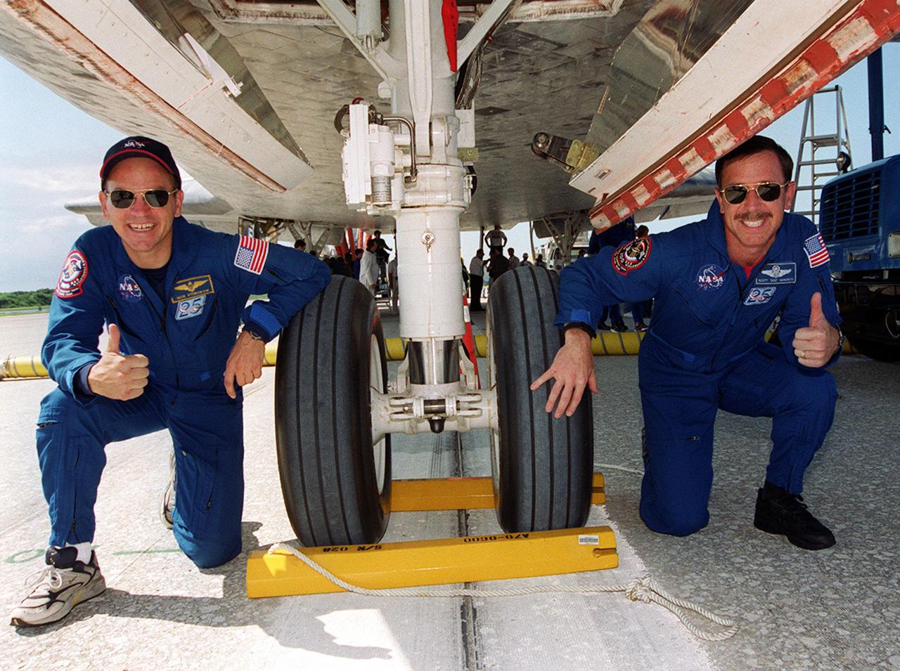 KENNEDY SPACE CENTER, Fla. - Following the landing of mission STS-105, Pilot Frederick 'Rick' Sturckow (left) and Commander Scott 'Doc' Horowitz give a jubilant thumbs up under orbiter Discovery sitting squarely on the center line of KSC's Shuttle Landing Facility runway 15. Main gear touchdown was at 2:22:58 p.m. EDT; wheel stop, at 2:24:06 p.m. EDT. The 11-day, 21-hour, 12-minute STS-105 mission accomplished the goals set for the 11th flight to the International Space Station: swapout of the resident Station crew; delivery of equipment, supplies and scientific experiments; and installation of the Early Ammonia Servicer and heater cables for the S0 truss on the Station. Discovery traveled 4.3 million miles on its 30th flight into space, the 106th mission of the Space Shuttle program. Out of five missions in 2001, the landing was the first to occur in daylight at KSC. 