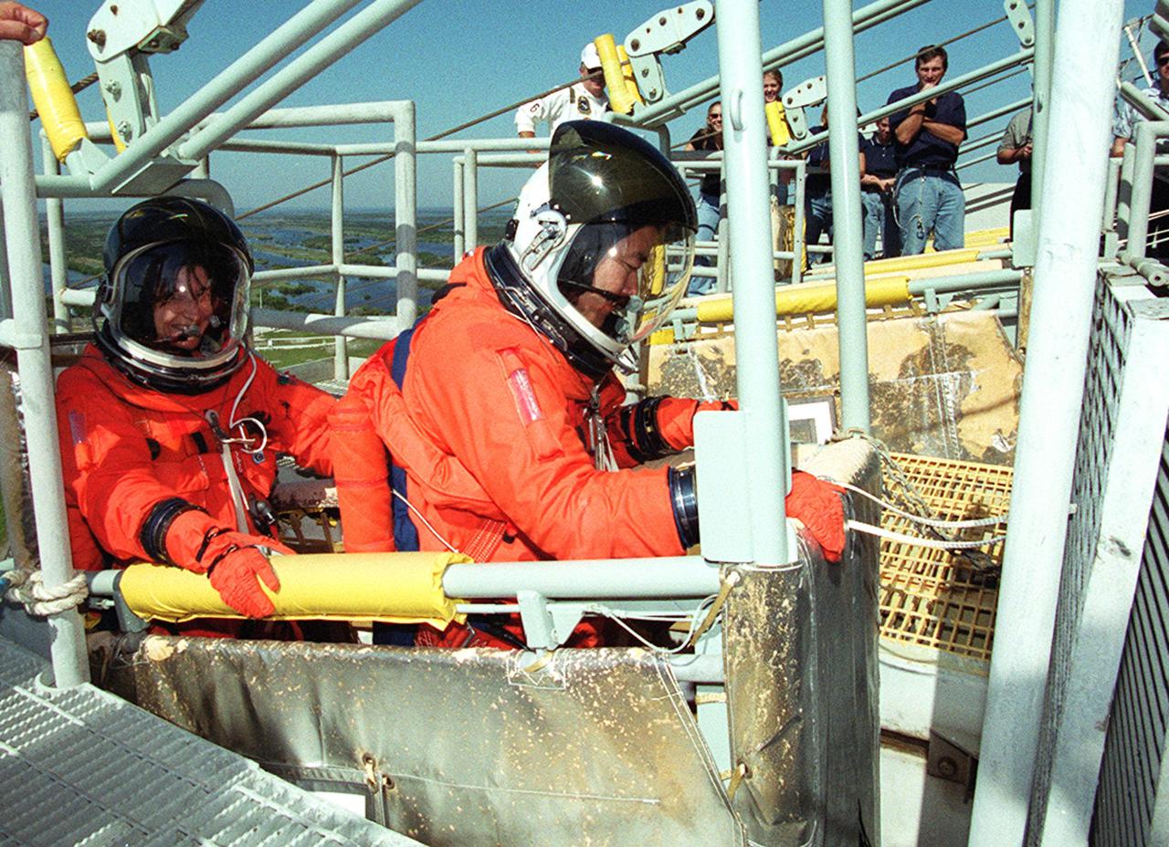 KENNEDY SPACE CENTER, Fla. --   STS-108 Mission Specialists Linda A. Godwin (left) and Daniel M. Tani (right) sit in the slidewire basket, part of the emergency egress system from the 195-foot level of the Fixed Service Structure on Launch Pad 39B. The training is part of Terminal Countdown Demonstration Test activities that also include a simulated launch countdown.. Launch of  Space Shuttle Endeavour on mission STS-108 is scheduled for Nov. 29 at 7:44 p.m. EST