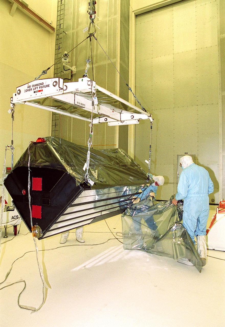 KENNEDY SPACE CENTER, Fla. --  Workers in Hangar AandE remove the wrapping from around the Advanced Camera for Surveys, which is suspended by an overhead crane. Part of the payload on the Hubble Space Telescope Servicing Mission, STS-109, the ACS will increase the discovery efficiency of the HST by a factor of ten. It consists of three electronic cameras and a complement of filters and dispersers that detect light from the ultraviolet to the near infrared (1200 - 10,000 angstroms).  The ACS was built through a collaborative effort between Johns Hopkins University, Goddard Space Flight Center, Ball Aerospace Corporation and Space Telescope Science Institute.  Tasks for the mission include replacing Solar Array 2 with Solar Array 3, replacing the Power Control Unit, removing the Faint Object Camera and installing the ACS, installing the Near Infrared Camera and Multi-Object Spectrometer (NICMOS) Cooling System, and installing New Outer Blanket Layer insulation on bays 5 through 8.  Mission STS-109 is scheduled for launch Feb. 14, 2002