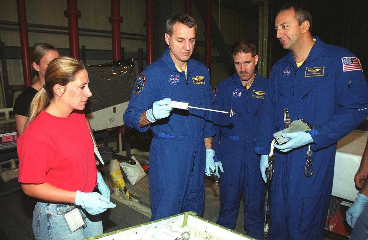 KENNEDY SPACE CENTER, Fla. - In the company of two technicians (left), STS-109 crew members look over equipment related to their mission. Holding the equipment is Mission Specialist Richard Linnehan (left); at center is Payload Commander John Grunsfeld; at right is Mission Specialist Michael Massimino. STS-109, the Hubble Space Telescope (HST) Servicing mission, is Massimino's first Shuttle flight. The crew is at KSC to take part in Crew Equipment Interface Test activities that include familiarization with the orbiter and equipment. The goal of the mission is to service the HST, replacing Solar Array 2 with Solar Array 3, replacing the Power Control Unit, removing the Faint Object Camera and installing the Advanced Camera for Surveys, installing the Near Infrared Camera and Multi-Object Spectrometer (NICMOS) Cooling System, and installing New Outer Blanket Layer insulation on bays 5 through 8. Mission STS-109 is scheduled for launch Feb. 14, 2002