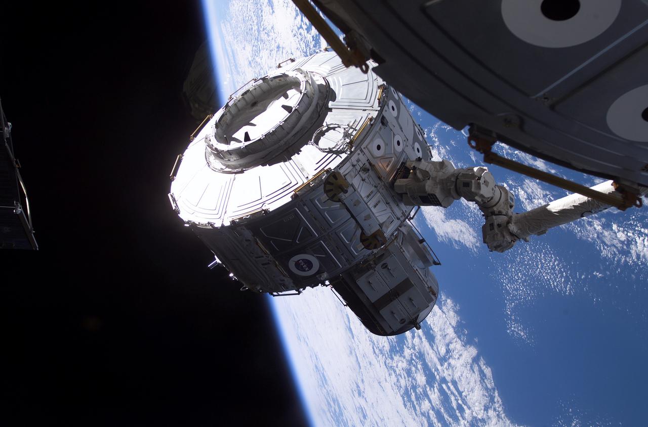 The Quest Airlock is in the process of being installed onto the starboard side of the Unity Node 1 of the International Space Station (ISS). Astronaut Susan J. Helms, Expedition Two flight engineer, used controls onboard the station to maneuver the Airlock into place with the Canadarm2, or Space Station Remote Manipulator System (SSRMS). The Joint Airlock is a pressurized flight element consisting of two cylindrical chambers attached end-to-end by a cornecting bulkhead and hatch. Once installed and activated, the ISS Airlock becomes the primary path for ISS space walk entry and departure for U.S. spacesuits, which are known as Extravehicular Mobility Units (EMUs). In addition, it is designed to support the Russian Orlan spacesuit for extravehicular activity (EVA). The Joint Airlock is 20-feet long, 13-feet in diameter and weighs 6.5 tons. It was built at the Marshall Space Flight Center (MSFC) by the Space Station prime contractor Boeing. The ISS Airlock has two main components: a crew airlock and an equipment airlock for storing EVA and EVA preflight preps. The Airlock was launched on July 21, 2001 aboard the Space Shuttle Orbiter Atlantis for the STS-104 mission.
