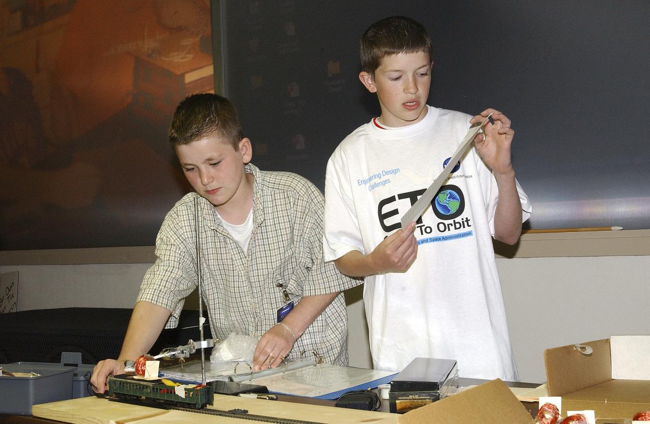In this photograph, Jeff Alden (left) and Justin O'Cornor, two middle school students at Lane Middle School in Portland, Oregon are demonstrating their Earth-to-Orbit (ETO) Design Challenge project at NASA Marshall Space Flight Center (MSFC) in Huntsville, Alabama. Jeff and Justin, who are just a couple of "typical teens," have been spending their time tackling some of the same challenges NASA engineers face when designing propulsion systems at MSFC. The ETO Design Challenge is a hands-on educational program, targeted to middle school students, in which students are assigned a project engaging in related design challenges in their classrooms under the supervision of their teachers. The project is valuable because it can be used by any student and any teacher, even those without technical backgrounds. Students in 12 states: Alabama, Arkansas, California, Colorado, Illinois, Missouri, Montana, New York, Ohio, Tennessee, Virginia, and Washington, are taking part in the MSFC's Earth-to-Orbit program. NASA uses such programs to support educational excellence while participating in educational outreach programs through centers around the country. The Oregon students' teacher, Joanne Fluvog, commented, "the biggest change I've seen is in the students' motivation and their belief in their ability to think." Both Justin and Jeff said being involved in a real engineering project has made them realize that "science is cool."