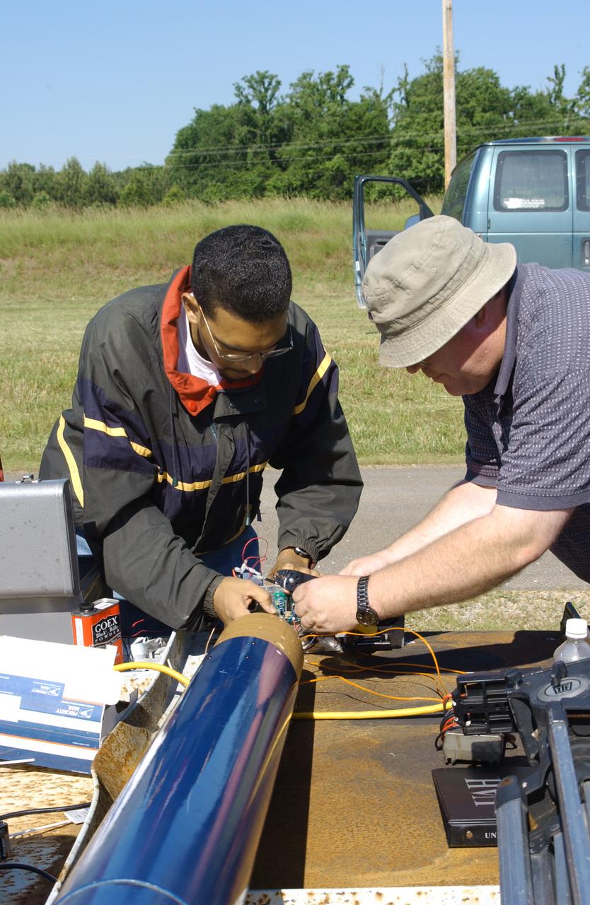 Filled with anticipation, students from two local universities, the University of Alabama in Huntsville (UAH), and Alabama Agricultural Mechanical University (AM), counted down to launch the rockets they designed and built at the Army test site on Redstone Arsenal in Huntsville, Alabama. The projected two-mile high launch culminated more than a year's work and demonstrated the student team's ability to meet the challenge set by the Marshall Space Flight Center's (MSFC) Student Launch Initiative (SLI) program to apply science and math to experience, judgment, and common sense, and proved to NASA officials that they have successfully built reusable launch vehicles (RLVs), another challenge set by NASA's SLI program. MSFC's SLI program is an educational effort that aims to motivate students to pursue careers in science, math, and engineering. It provides the students with hands-on, practical aerospace experience. In this picture, a student from AM and his mentor install their payload into the launch vehicle which was built by the team of UAH students. The scientific payload, developed and built by the team of AM students, measured the amount of hydrogen produced during electroplating with nickel in a brief period of micrgravity.