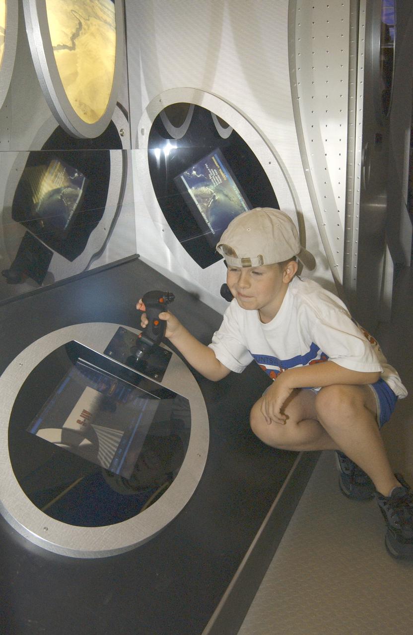 This photograph shows Justin Varnadore, son of a Marshall TV employee, at the controls of one of the many displays within the Starship 2040 exhibit on display at Joe Davis Stadium in Huntsville, Alabama. Developed by the Space Transportation Directorate at Marshall Space Flight Center (MSFC), the Starship 2040 exhibit is housed in a 48-ft (14.6-m) tractor and trailer rig, permitting it to travel around the Nation, demonstrating NASA's vision of what commercial spaceflight might be like 40 years from now. All the irnovations suggested aboard the exhibit (automated vehicle health monitoring systems, high-energy propulsion drive, navigational aids, and emergency and safety systems) are based on concepts and technologies now being studied at NASA Centers and partner institutions around the Nation. NASA is the Nation's premier agency for development of the space transportation system, including future-generation reusable launch vehicles. Such systems, the keys to a "real" Starship 2040, require revolutionary advances in critical aerospace technologies, from thermal, magnetic, chemical, and propellantless propulsion systems to new energy sources such as space solar power or antimatter propulsion. These and other advances are now being studied, developed, and tested at NASA field centers and partner institutions all over the Nation.