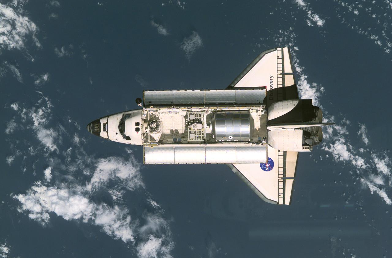 This is a view of the Space Shuttle Discovery as it approaches the International Space Station (ISS) during the STS-105 mission. Visible in the payload bay of Discovery are the Multipurpose Logistics Module (MPLM) Leonardo at right, which stores various supplies and experiments to be transferred into the ISS; at center, the Integrated Cargo Carrier (ICC) which carries the Early Ammonia Servicer (EAS); and two Materials International Space Station Experiment (MISSE) containers at left. Aboard Discovery were the ISS Expedition Three crew, who were to replace the Expedition Two crew that had been living on the ISS for the past five months.