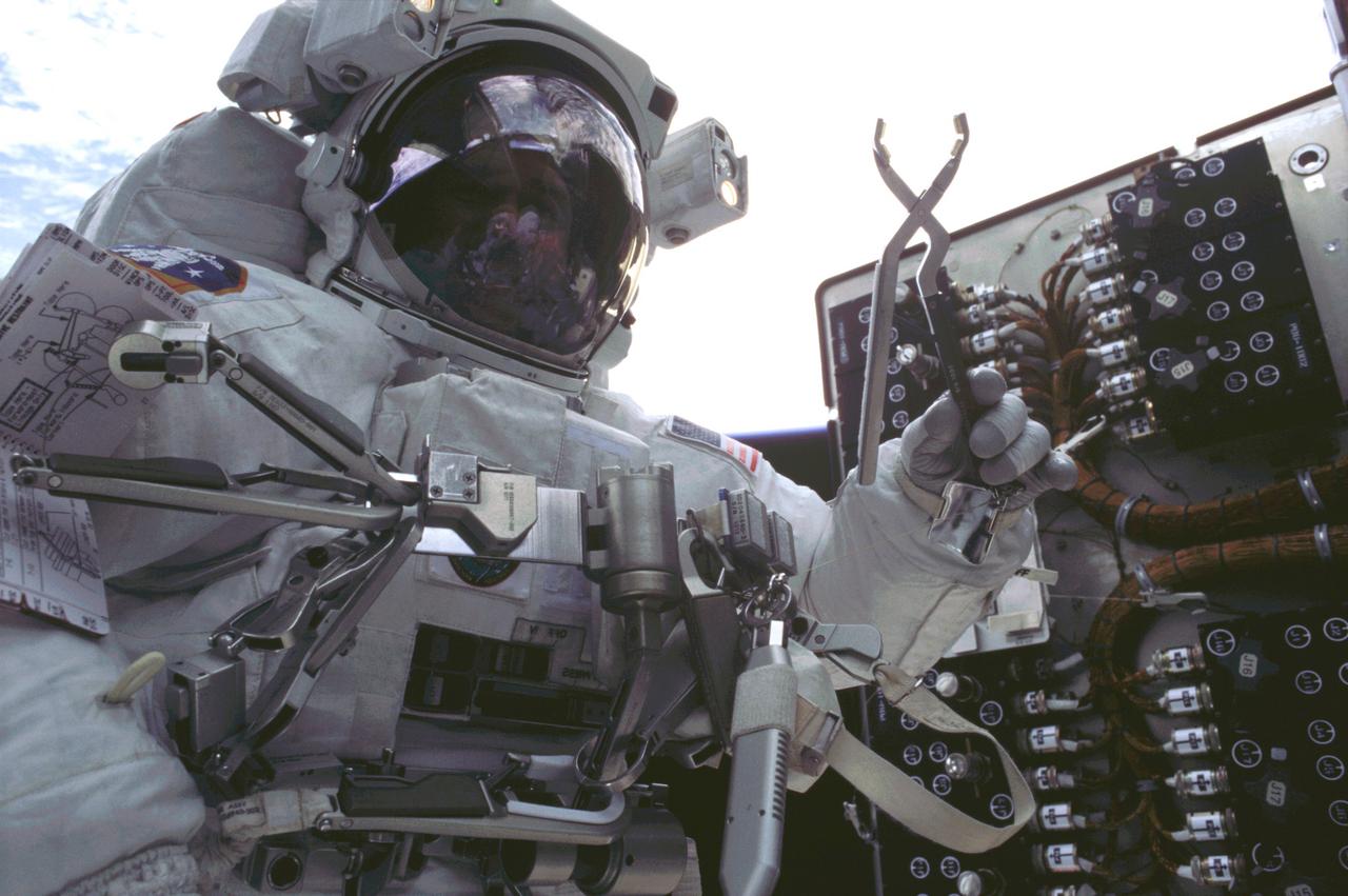 This is an onboard photo of Astronaut John M. Grunsfield, STS-109 payload commander, participating in the third of five spacewalks to perform work on the Hubble Space Telescope (HST). On this particular walk, Grunsfield, joined by Astronaut Richard M. Lirnehan, turned off the telescope in order to replace its power control unit (PCU), the heart of the HST's power system. The telescope was captured and secured on a work stand in Columbia's payload bay using Columbia's robotic arm, where crew members completed system upgrades to the HST. Included in those upgrades were: replacement of the solar array panels; replacement of the power control unit (PCU); replacement of the Faint Object Camera (FOC) with a new advanced camera for Surveys (ACS); and installation of the experimental cooling system for the Hubble's Near-Infrared Camera and Multi-object Spectrometer (NICMOS), which had been dormant since January 1999 when its original coolant ran out. The Marshall Space Flight Center had the responsibility for the design, development, and construction of the HST, which is the most complex and sensitive optical telescope ever made, to study the cosmos from a low-Earth orbit. The HST detects objects 25 times fainter than the dimmest objects seen from Earth and provides astronomers with an observable universe 250 times larger than is visible from ground-based telescopes, perhaps as far away as 14 billion light-years. The HST views galaxies, stars, planets, comets, possibly other solar systems, and even unusual phenomena such as quasars, with 10 times the clarity of ground-based telescopes. Launched March 1, 2002 the STS-109 HST servicing mission lasted 10 days, 22 hours, and 11 minutes. It was the 108th flight overall in NASA's Space Shuttle Program.
