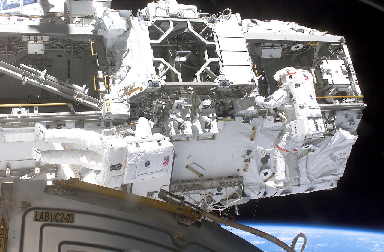 STS-110 Mission astronauts Steven L. Smith (right) and Rex J. Walheim work in tandem on the third scheduled EVA session in which they released the locking bolts on the Mobile Transporter and rewired the Station's robotic arm (out of frame). Part of the Destiny laboratory and a glimpse of the Earth's horizon are seen in the lower portion of this digital image. The STS-110 mission prepared the International Space Station (ISS) for future spacewalks by installing and outfitting the S0 (S-zero) Truss and the Mobile Transporter. The 43-foot-long S0 truss weighing in at 27,000 pounds was the first of 9 segments that will make up the Station's external framework that will eventually stretch 356 feet (109 meters), or approximately the length of a football field. This central truss segment also includes a flatcar called the Mobile Transporter and rails that will become the first "space railroad," which will allow the Station's robotic arm to travel up and down the finished truss for future assembly and maintenance. The completed truss structure will hold solar arrays and radiators to provide power and cooling for additional international research laboratories from Japan and Europe that will be attached to the Station. Milestones of the S-110 mission included the first time the ISS robotic arm was used to maneuver spacewalkers around the Station and marked the first time all spacewalks were based out of the Station's Quest Airlock. It was also the first Shuttle to use three Block II Main Engines. The Space Shuttle Orbiter Atlantis, STS-110 mission, was launched April 8, 2002 and returned to Earth April 19, 2002.