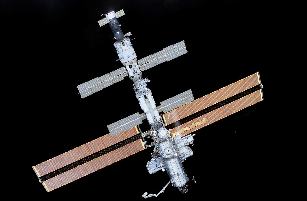 This close-up view of the International Space Station (ISS), newly equipped with its new 27,000-pound S0 (S-zero) truss, was photographed by an astronaut aboard the Space Shuttle Atlantis STS-110 mission following its undocking from the ISS. The STS-110 mission prepared the Station for future spacewalks by installing and outfitting the 43-foot-long S0 truss and preparing the first railroad in space, the Mobile Transporter. The 27,000 pound S0 truss was the first of 9 segments that will make up the Station's external framework that will eventually stretch 356 feet (109 meters), or approximately the length of a football field. This central truss segment also includes a flatcar called the Mobile Transporter and rails that will become the first "space railroad," which will allow the Station's robotic arm to travel up and down the finished truss for future assembly and maintenance. The completed truss structure will hold solar arrays and radiators to provide power and cooling for additional international research laboratories from Japan and Europe that will be attached to the Station. STS-110 Extravehicular Activity (EVA) marked the first use of the Station's robotic arm to maneuver spacewalkers around the Station and was the first time all of a Shuttle crew's spacewalks were based out of the Station's Quest Airlock. It was also the first Shuttle to use three Block II Main Engines. The Space Shuttle Orbiter Atlantis STS-110 mission, was launched April 8, 2002 and returned to Earth April 19, 2002.