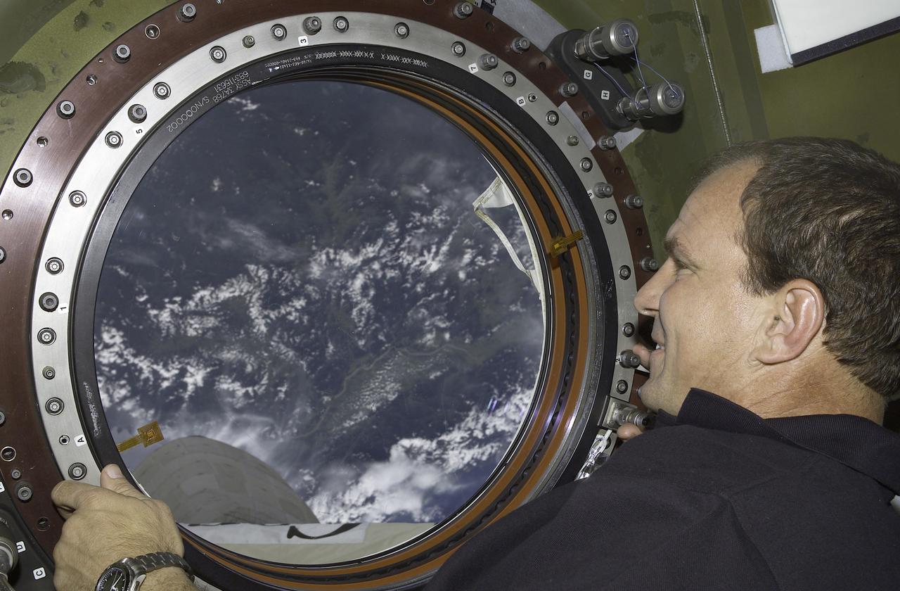 Astronaut Michael J. Bloomfield, STS-110 mission commander, looks through the Earth observation window in the Destiny laboratory aboard the International Space Station (ISS). The STS-110 mission prepared the ISS for future spacewalks by installing and outfitting the S0 (S-zero) truss and the Mobile Transporter. The 43-foot-long S0 Truss, weighing in at 27,000 pounds, was the first of 9 segments that will make up the Station's external framework that will eventually stretch 356 feet (109 meters), or approximately the length of a football field. This central truss segment also includes a flatcar called the Mobile Transporter and rails that will become the first "space railroad," which will allow the Station's robotic arm to travel up and down the finished truss for future assembly and maintenance. The completed truss structure will hold solar arrays and radiators to provide power and cooling for additional international research laboratories from Japan and Europe that will be attached to the Station. Milestones of the STS-110 mission included the first time the ISS robotic arm was used to maneuver spacewalkers around the Station and marked the first time all spacewalks were based out of the Station's Quest Airlock. It was also the first Shuttle to use three Block II Main Engines. The Space Shuttle Orbiter Atlantis, STS-110 mission, was launched April 8, 2002 and returned to Earth April 19, 2002.
