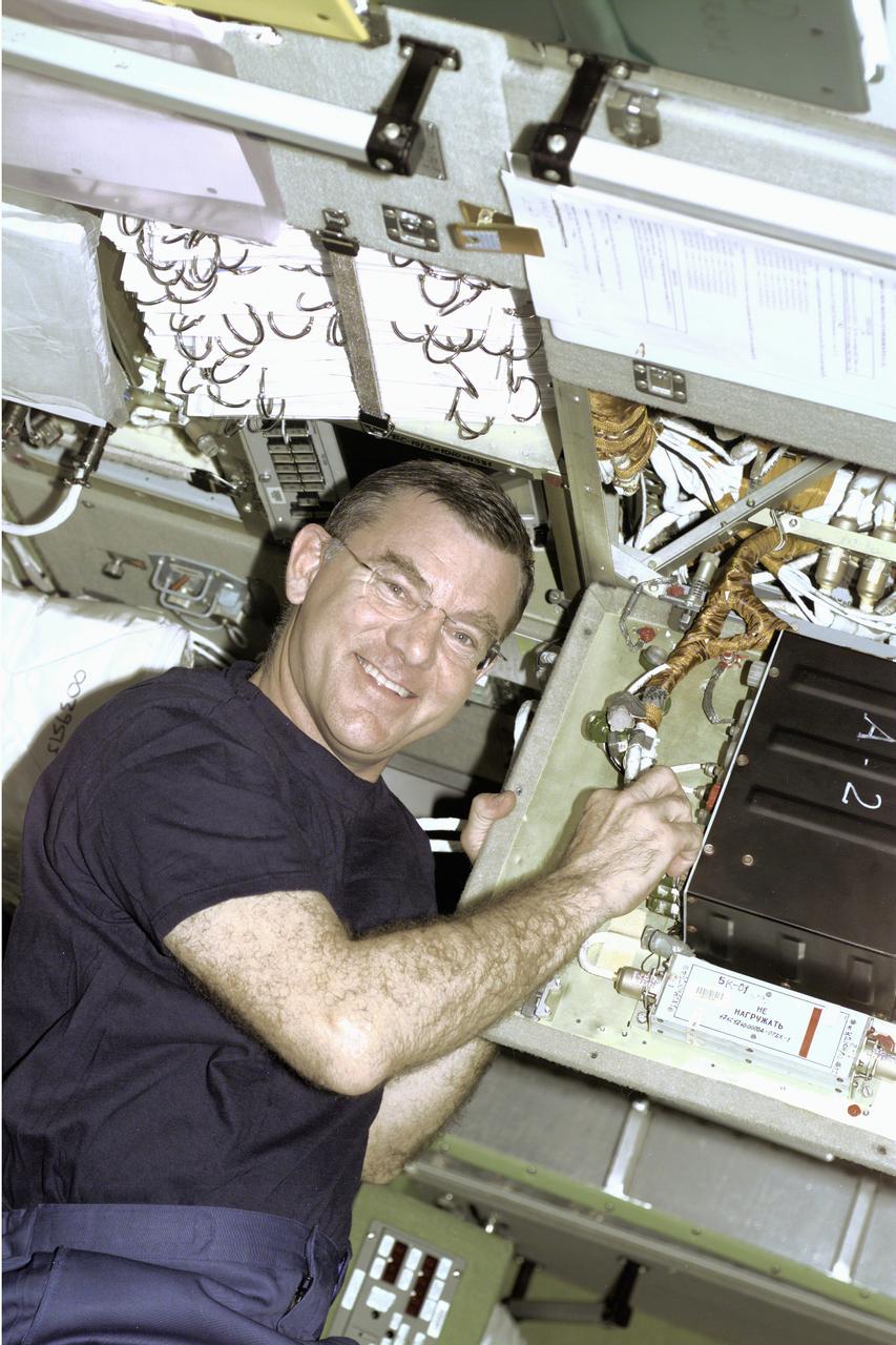 Astronaut James S. Voss, Expedition Two flight engineer, performs an electronics task in the Russian Zvezda Service Module on the International Space Station (ISS). Zvezda is linked to the Russian-built Functional Cargo Block (FGB), or Zarya, the first component of the ISS. Zarya was launched on a Russian Proton rocket prior to the launch of Unity, the first U.S.-built component to the ISS. Zvezda (Russian word for star), the third component of the ISS and the primary Russian contribution to the ISS, was launched by a three-stage Proton rocket on July 12, 2000. Zvezda serves as the cornerstone for early human habitation of the station, providing living quarters, a life support system, electrical power distribution, a data processing system, a flight control system, and a propulsion system. It also provides a communications system that includes remote command capabilities from ground flight controllers. The 42,000-pound module measures 43 feet in length and has a wing span of 98 feet. Similar in layout to the core module of Russia's Mir space station, it contains 3 pressurized compartments and 13 windows that allow ultimate viewing of Earth and space.