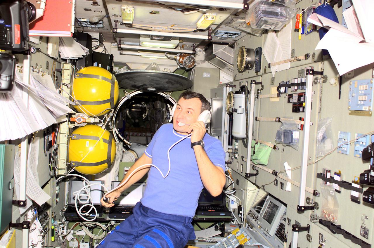 Aboard the International Space Station (ISS), Cosmonaut and Expedition Three flight engineer Vladimir N. Dezhurov, representing Rosaviakosmos, talks with flight controllers from the Zvezda Service Module. Russian-built Zvezda is linked to the Functional Cargo Block (FGB), or Zarya, the first component of the ISS. Zarya was launched on a Russian Proton rocket prior to the launch of Unity. The third component of the ISS, Zvezda (Russian word for star), the primary Russian contribution to the ISS, was launched by a three-stage Proton rocket on July 12, 2000. Zvezda serves as the cornerstone for early human habitation of the Station, providing living quarters, a life support system, electrical power distribution, a data processing system, flight control system, and propulsion system. It also provides a communications system that includes remote command capabilities from ground flight controllers. The 42,000-pound module measures 43 feet in length and has a wing span of 98 feet. Similar in layout to the core module of Russia's Mir space station, it contains 3 pressurized compartments and 13 windows that allow ultimate viewing of Earth and space.