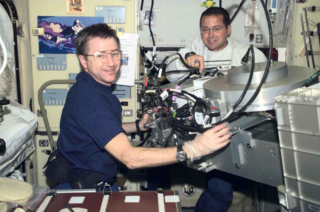 Astronauts Frank L. Culbertson, Jr. (left), Expedition Three mission commander, and Daniel W. Bursch, Expedition Four flight engineer, work in the Russian Zvezda Service Module on the International Space Station (ISS). Zvezda is linked to the Russian built Functional Cargo Block (FGB), or Zarya, the first component of the ISS. Zarya was launched on a Russian Proton rocket prior to the launch of Unity. The third component of the ISS, Zvezda (Russian word for star), the primary Russian contribution to the ISS, was launched by a three-stage Proton rocket on July 12, 2000. Zvezda serves as the cornerstone for early human habitation of the Station, providing living quarters, a life support system, electrical power distribution, a data processing system, a flight control system, and a propulsion system. It also provides a communications system that includes remote command capabilities from ground flight controllers. The 42,000 pound module measures 43 feet in length and has a wing span of 98 feet. Similar in layout to the core module of Russia's Mir space station, it contains 3 pressurized compartments and 13 windows that allow ultimate viewing of Earth and space.