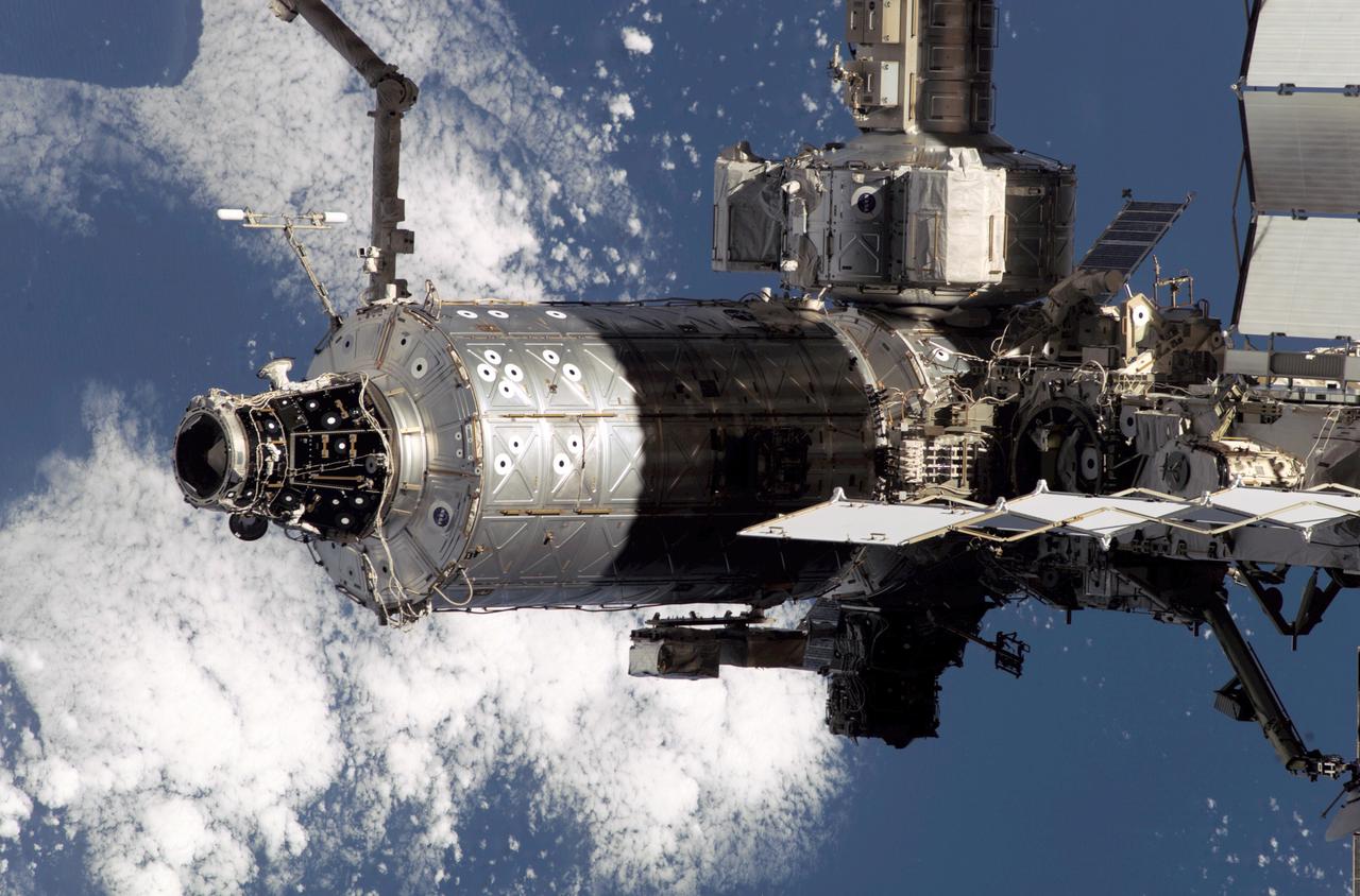 As seen through a window on the Space Shuttle Endeavor's aft flight deck, the International Space Station (ISS), with its newly-staffed crew of three, Expedition Four, is contrasted against a patch of the blue and white Earth. The Destiny laboratory is partially covered with shadows in the foreground. The photo was taken during the departure of the Earth-bound Endeavor, bringing to a close the STS-108 mission, the 12th Shuttle mission to visit the ISS.