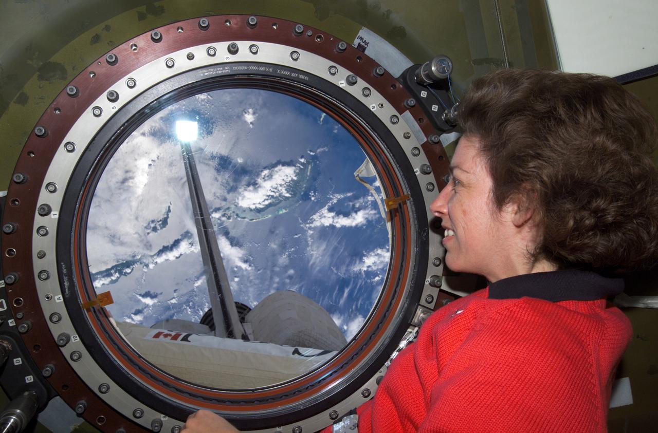 Astronaut Ellen Ochoa, STS-110 mission specialist, looks through the window of the Destiny laboratory on the International Space Station (ISS) as she views portions of the Space Shuttle Atlantis and the Canadarm2. It was during the STS-110 mission that the Canadian-developed ISS robotic arm was used to maneuver spacewalkers around the station for the first time. The STS-110 mission, carried by the Space Shuttle Orbiter Atlantis, was launched on April 8, 2002.