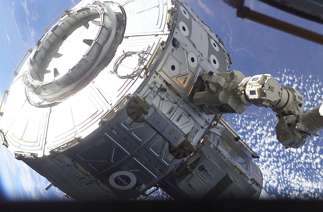 At the control of Expedition Two Flight Engineer Susan B. Helms, the newly-installed Canadian-built Canadarm2, Space Station Remote Manipulator System (SSRMS) maneuvers the Quest Airlock into the proper position to be mated onto the starboard side of the Unity Node I during the first of three extravehicular activities (EVA) of the STS-104 mission. The Quest Airlock makes it easier to perform space walks, and allows both Russian and American spacesuits to be worn when the Shuttle is not docked with the International Space Station (ISS). American suits will not fit through Russion airlocks at the Station. The Boeing Company, the space station prime contractor, built the 6.5-ton (5.8 metric ton) airlock and several other key components at the Marshall Space Flight Center (MSFC), in the same building where the Saturn V rocket was built. Installation activities were supported by the development team from the Payload Operations Control Center (POCC) located at the MSFC and the Mission Control Center at NASA's Johnson Space Flight Center in Houston, Texas.