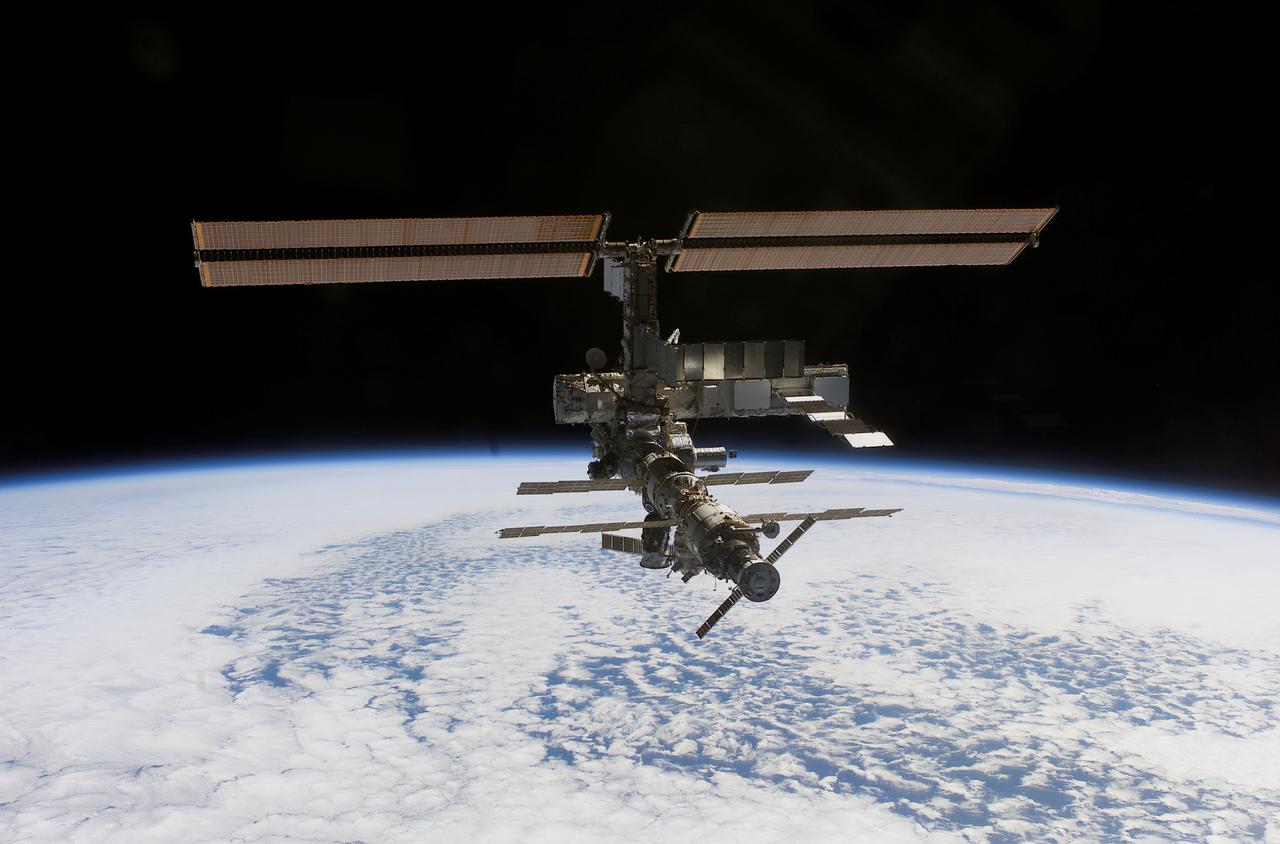 This image of the International Space Station (ISS) was photographed by one of the crewmembers of the STS-112 mission following separation from the Space Shuttle Orbiter Atlantis as the orbiter pulled away from the ISS. The primary payloads of this mission, International Space Station Assembly Mission 9A, were the Integrated Truss Assembly S1 (S-One), the Starboard Side Thermal Radiator Truss, and the Crew Equipment Translation Aid (CETA) cart to the ISS. The S1 truss provides structural support for the orbiting research facility's radiator panels, which use ammonia to cool the Station's complex power system. The S1 truss was attached to the S0 (S Zero) truss, which was launched on April 8, 2002 aboard the STS-110, and flows 637 pounds of anhydrous ammonia through three heat-rejection radiators. The truss is 45-feet long, 15-feet wide, 10-feet tall, and weighs approximately 32,000 pounds. The CETA cart was attached to the Mobil Transporter and will be used by assembly crews on later missions. Manufactured by the Boeing Company in Huntington Beach, California, the truss primary structure was transferred to the Marshall Space Flight Center in February 1999 for hardware installations and manufacturing acceptance testing. The launch of the STS-112 mission occurred on October 7, 2002, and its 11-day mission ended on October 18, 2002.