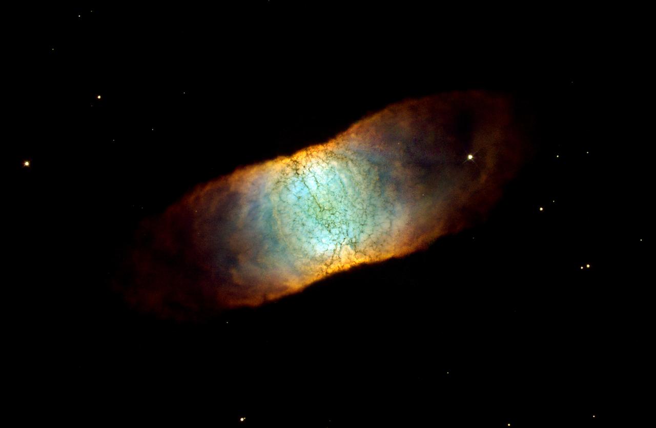 This Hubble Space Telescope image reveals a rainbow of colors in this dying star, called IC 446. Like many other so-called planetary nebulae, IC 4406 exhibits a high degree of symmetry. The nebula's left and right halves are nearly mirror images of the other. If we could fly around IC 446 in a spaceship, we would see that the gas and dust form a vast donut of material streaming outward from the dying star. We do not see the donut shape in this photograph because we are viewing IC 4406 from the Earth-orbiting HST. From this vantage point, we are seeing the side of the donut. This side view allows us to see the intricate tendrils of material that have been compared to the eye's retina. In fact, IC 4406 is dubbed the "Retina Nebula." The donut of material confines the intense radiation coming from the remnant of the dying star. Gas on the inside of the donut is ionized by light from the central star and glows. Light from oxygen atoms is rendered blue in this image; hydrogen is shown as green, and nitrogen as red. The range of color in the final image shows the differences in concentration of these three gases in the nebula. This image is a composite of data taken by HST's Wide Field Planetary Camera 2 in June 2001 and in January 2002 by Bob O'Dell (Vanderbilt University) and collaborators, and in January by the Hubble Heritage Team (STScI). Filters used to create this color image show oxygen, hydrogen, and nitrogen gas glowing in this object.