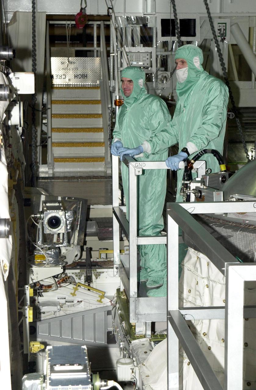 KENNEDY SPACE CENTER, FLA. -- In the Orbiter Processing Facility, STS-110 Mission Specialists Rex Walheim (left) and Steven Smith (right) look over the payload bay of Atlantis during Crew Equipment Integration Test activities, which include familiarization with the vehicle and payload. .  The mission, 13th assembly flight to the International Space Station, includes the Integrated Truss Structure S0.    The ITS S0 is the center segment on the Space Station, part of the 300-foot (91-meter) truss attached to the U.S. Lab. By assembly completion, four more truss segments will attach to either side of the S0 truss.  STS-110 is scheduled to launch April 4, 2002