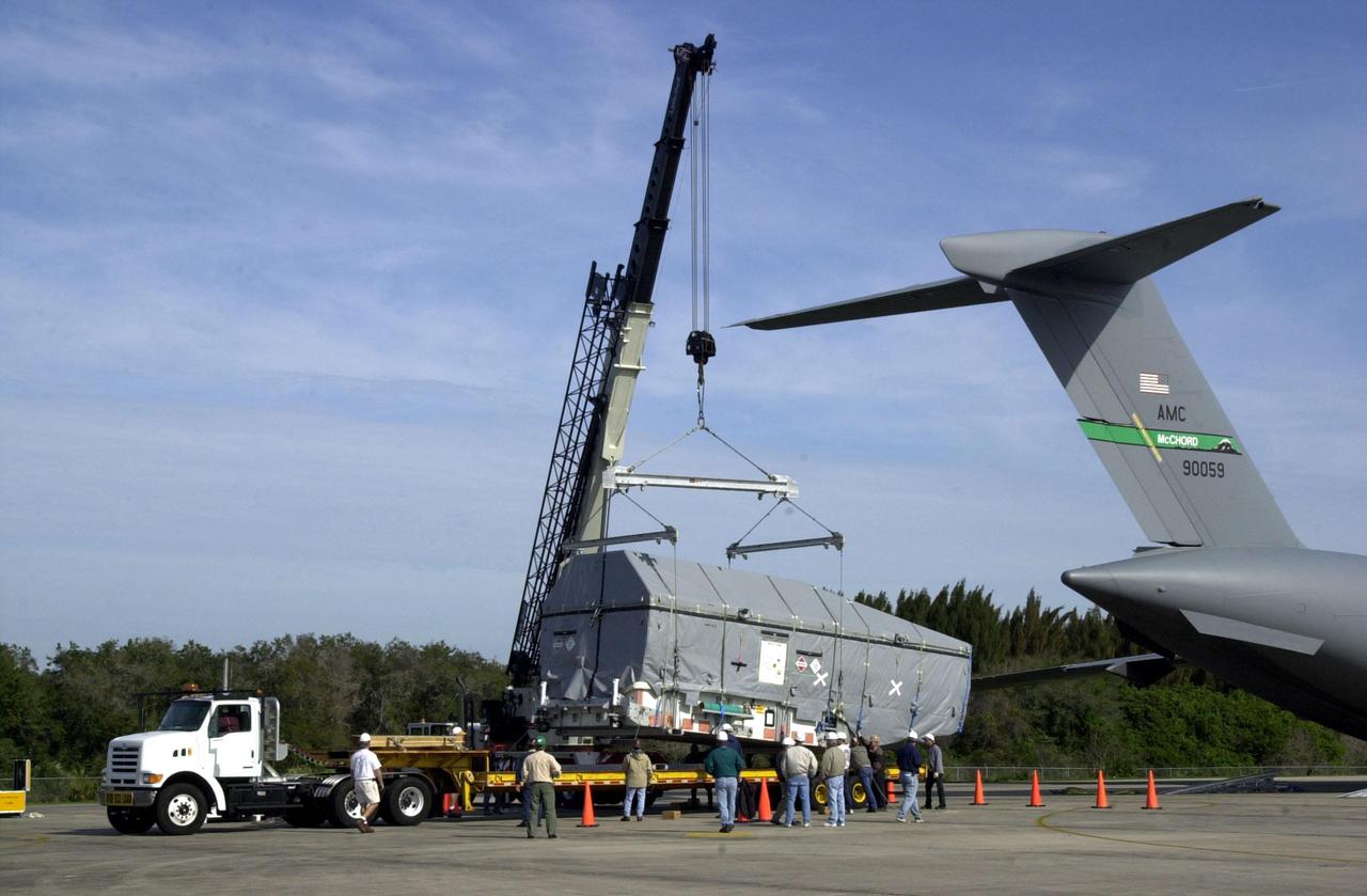 KENNEDY SPACE CENTER, FLA. -- At KSC's Shuttle Landing Facility, the Tracking and Data Relay Satellite-I (TDRS-I) is lifted onto a transporter after being offloaded from the Air Force C-17 air cargo plane at right. The second in a new series of telemetry satellites, TDRS-I replenishes the existing on-orbit fleet of six spacecraft.  The TDRS System is the primary source of space-to-ground voice, data and telemetry for the Space Shuttle.  It also provides communications with the International Space Station and scientific spacecraft in low-Earth orbit such as the Hubble Space Telescope.  This new advanced series of satellites will extend the availability of TDRS communications services until about 2017. TDRS-I will undergo processing in the Spacecraft Assembly and Encapsulation Facility-2 (SAEF-2) to prepare it for launch March 8 aboard a Lockheed Martin Atlas IIA rocket from Pad 36-A, Cape Canaveral Air Force Station