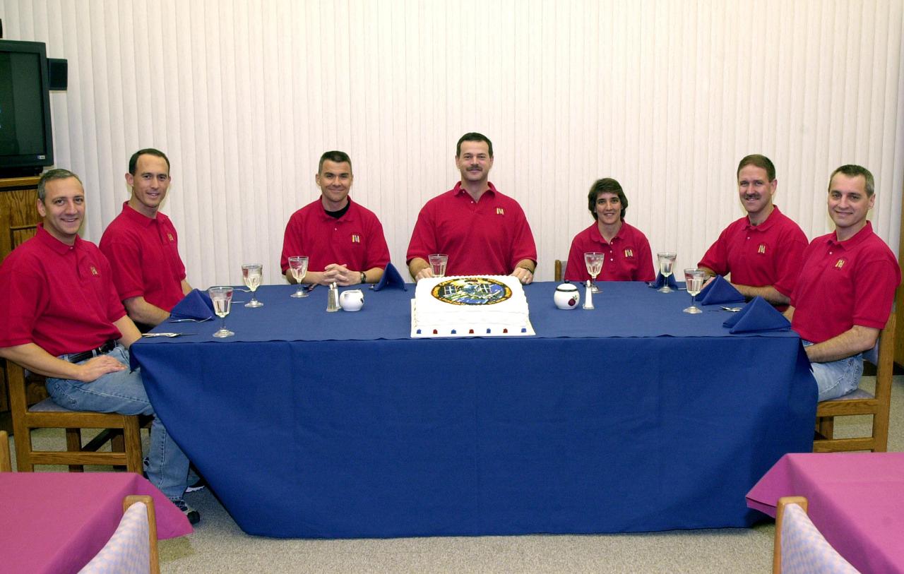 KENNEDY SPACE CENTER, Fla. -- The STS-109 crew enjoys an early morning snack that includes a symbolic cake with the mission logo, part of a ritual before a launch.  Seated, left to right, are MIssion Specialists Michael Massimino and James Newman; Pilot Duane Carey; Commander Scott Altman; and Mission Specialists Nancy Currie, John Grunsfeld and Richard Linnehan.  On mission STS-109, the crew will capture the Hubble Space Telescope using the Shuttle’s robotic arm and secure it on a workstand in Columbia's payload bay.  Four mission specialists will perform five scheduled spacewalks to complete system upgrades to the telescope. More durable solar arrays, a large gyroscopic assembly to help point the telescope properly, a new telescope power control unit, and a cooling system to restore the use of a key infrared camera and spectrometer unit, which has been dormant since 1999, will all be installed. In addition, the telescope's view of the Universe will be improved with the addition of the Advanced Camera for Surveys (ACS), which replaces the Faint Object Camera, the last of Hubble's original instruments. Mission STS-109 is the 27th flight of the orbiter Columbia and the 108th flight overall in NASA’s Space Shuttle program. After the 11-day mission, STS-109 is scheduled to land about 4:35 a.m. EST on March 12