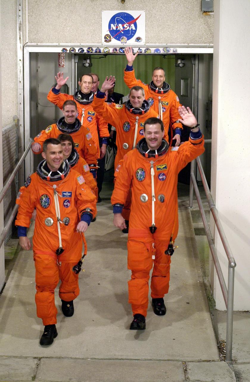 KENNEDY SPACE CENTER, Fla. -  The STS-109 crew members wave to onlookers as they stride out from the Operations and Checkout Building, eager to get to the launch pad.   They are, from front to back, Pilot Duane G. Carey (left) and Commander Scott D. Altman (right); Mission Specialist Nance Jane Currie; Payload Commander John M. Grunsfeld (left) and Richard M. Linnehan (right); James H. Newman (left) and Michael J. Massimino (right).  On mission STS-109, the crew will capture the Hubble Space Telescope using the Shuttle's robotic arm and secure it on a workstand in Columbia's payload bay.  Four mission specialists will perform five scheduled spacewalks to complete system upgrades to the telescope. More durable solar arrays, a large gyroscopic assembly to help point the telescope properly, a new telescope power control unit, and a cooling system to restore the use of a key infrared camera and spectrometer unit, which has been dormant since 1999, will all be installed. In addition, the telescope's view of the Universe will be improved with the addition of the Advanced Camera for Surveys (ACS), which replaces the Faint Object Camera, the last of Hubble's original instruments. Mission STS-109 is the 27th flight of the orbiter Columbia and the 108th flight overall in NASA's Space Shuttle program. After the 11-day mission, STS-109 is scheduled to land about 4:35 a.m. EST on March 12