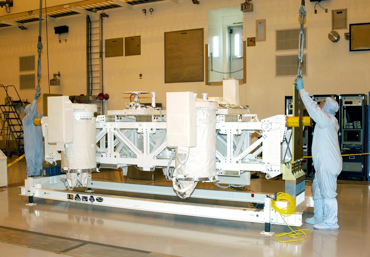 KENNEDY SPACE CENTER, FLA. -- In the Multi-Payload Processing Facility (MPPF), workers attach a crane to the Hitchhiker Bridge that holds several Get-Away Special canisters (GAS cans) for mission ST-107. The bridge is being moved to a workstand in the MPPF. The bridge is a carrier for the Fast Reaction Experiments Enabling Science, Technology, Applications and Research (FREESTAR) that incorporates eight high priority secondary attached shuttle experiments on mission STS-107. A research mission, the primary payload is the first flight of the SHI Research Double Module (SHI_RDM), also known as SPACEHAB. The experiments range from material sciences to life sciences. STS-107 is scheduled to launch July 11, 2002
