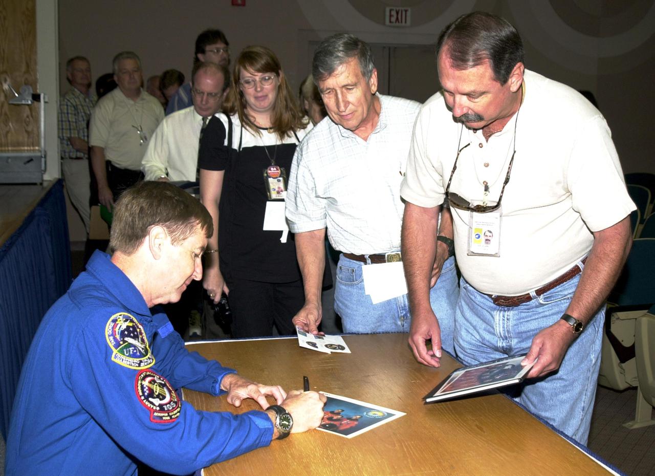 KENNEDY SPACE CENTER, FLA. --  Astronaut Frank Culbertson (left) autographs photos for KSC employees following his presentation on his experiences as commander of Expedition 3 aboard the International Space Station.  Culbertson began his stay on ISS in August 2001 and returned Dec. 17 aboard Endeavour after mission STS-108.