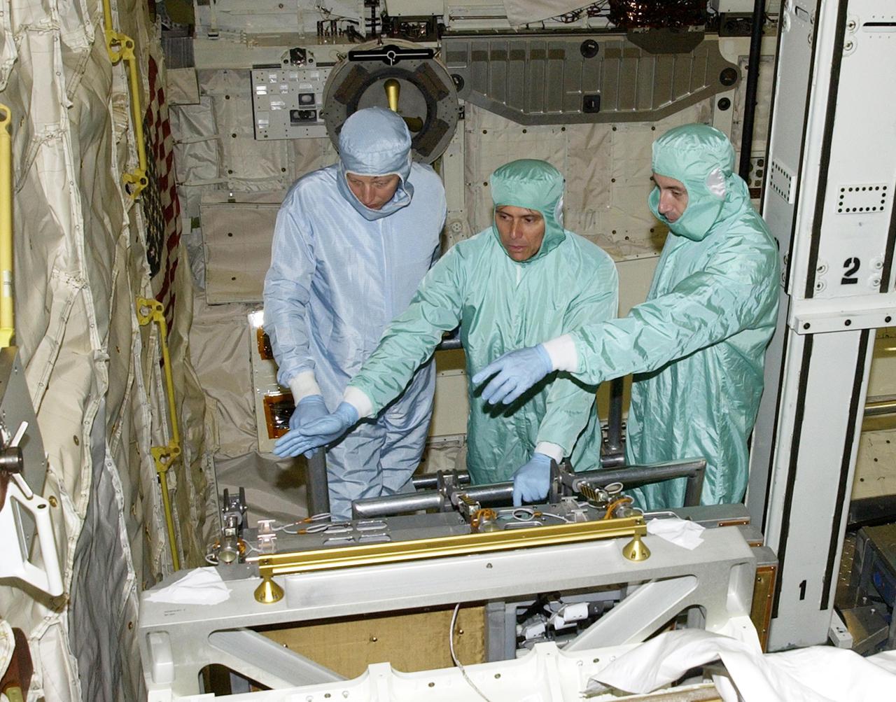 KENNEDY SPACE CENTER, FLA. - In the Orbiter Processing Facility, STS-111 Mission Specialists Franklin Chang-Diaz (center) and Phillippe Perrin (right) look over equipment with a trainer (left) in orbiter Endeavour.  Perrin is with the French Space Agency (CNES).  Perrin and Chang-Diaz, with other crew members, are taking part in a Crew Equipment Interface Test in preparation for launch.  Mission STS-111 will carry to the International Space Station the Multipurpose Logistics Module (MPLM), filled with experiment racks and three stowage and resupply racks, and the Mobile Base System (MBS), which will attach to the Mobile Transporter and complete the Canadian Mobile Servicing System, or MSS. The Station's mechanical arm will then have the capability to 'inchworm' from the U.S. Lab to the MSS and travel along the truss to work sites on the Station.  Launch of Endeavour on mission STS-111 is scheduled for May 30, 2002