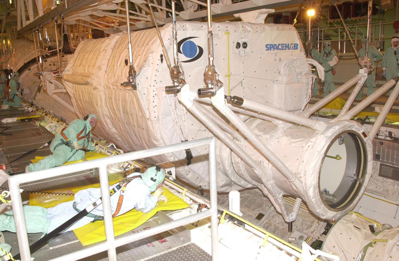 KENNEDY SPACE CENTER, FLA. - Workers in the Orbiter Processing Facility keep watch as the SHI Research Double Module (SHI_RDM) (right) and Hitchhiker Carrier (left) are lowered into Columbia's payload bay for mission STS-107, a research mission. SHI_RDM is the primary payload, with experiments ranging from material sciences to life sciences (many rats). Also, the Fast Reaction Experiments Enabling Science, Technology, Applications and Research (FREESTAR) that is on the Hitchhiker Carrier incorporates eight high priority secondary attached shuttle experiments. STS-107 is scheduled to launch July 19, 2002