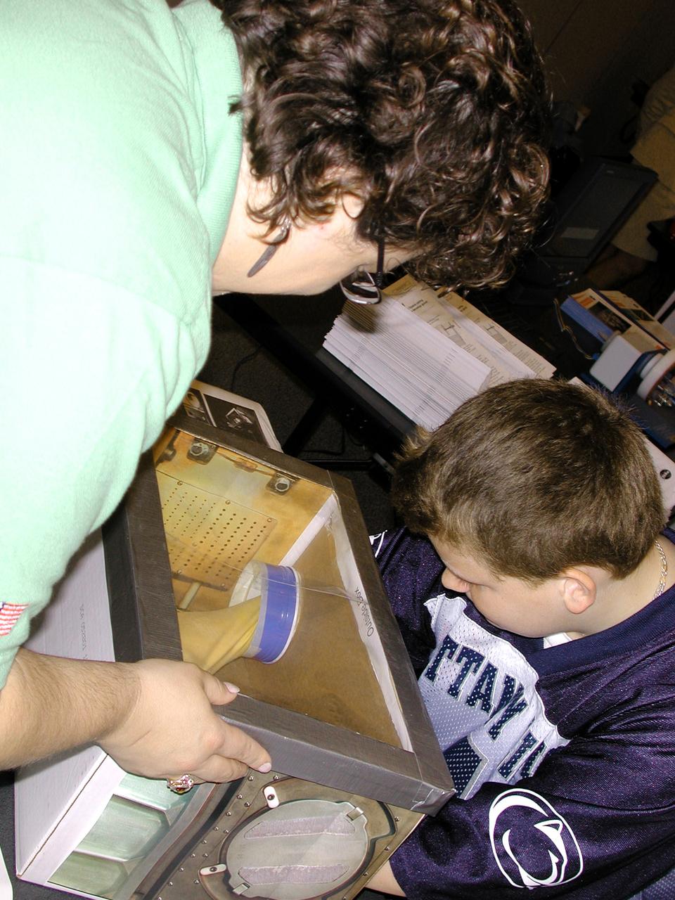 Carla Rosenberg of the National Center for Microgravity Research explains the operation of the Middeck Glovebox to a middle school student. The activity was part of the Space Research and You education event held by NASA's Office of Biological and Physical Research on June 25, 2002, in Arlington, VA, to highlight the research that will be conducted on STS-107.
